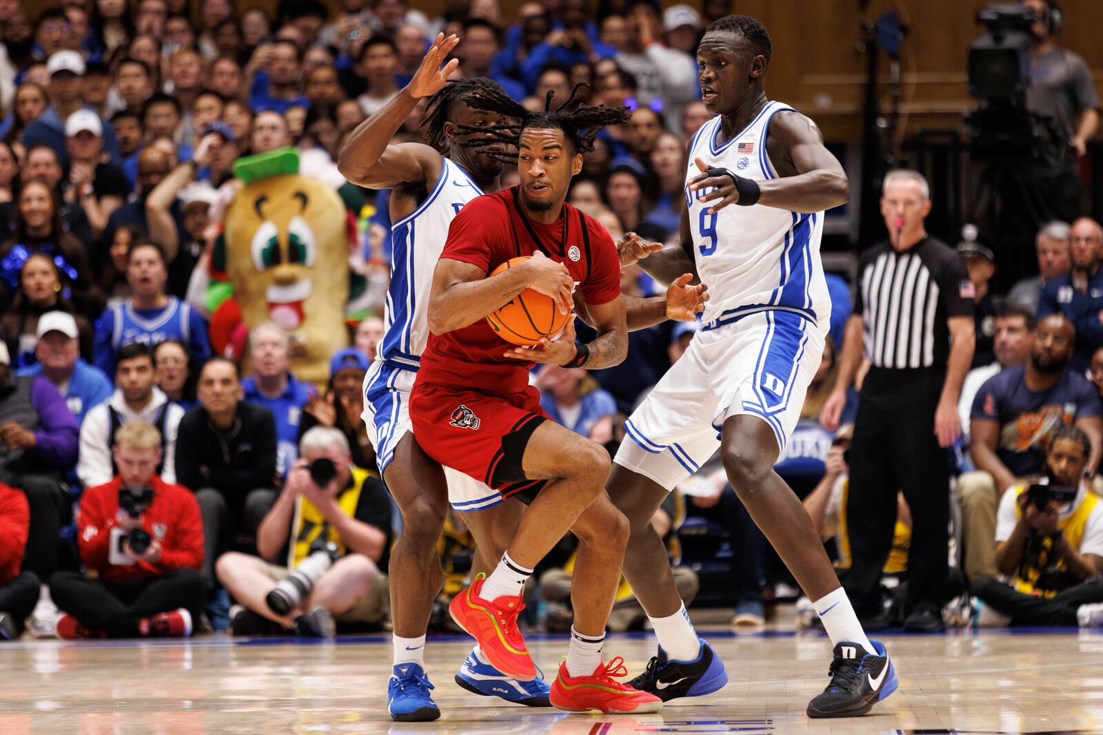 North Carolina State's Jayden Taylor, center, handles the ball between Duke's Sion James, left, and Khaman Malauch (9) during the second half of an NCAA college basketball game in Durham, N.C., Monday, Jan. 27, 2025. (AP Photo/Ben McKeown)