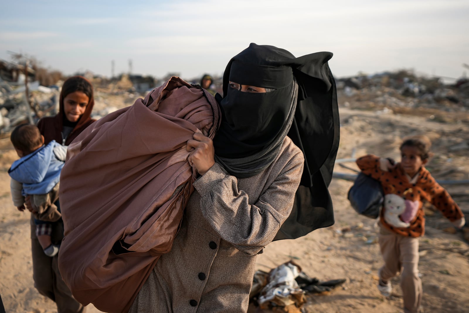 Azhar Abu Sheiban, center, and her family members return to their home in Rafah, days after the ceasefire deal between Israel and Hamas, southern Gaza Strip, Tuesday, Jan. 21, 2025. (AP Photo/Abdel Kareem Hana)