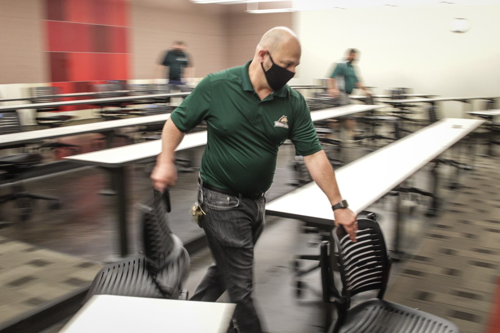 Wright State University employee Jim Click removes chairs from a classroom to achieve the correct distance between students. The university will offer classes mostly online but there will be some in-person classes. JIM NOELKER/STAFF