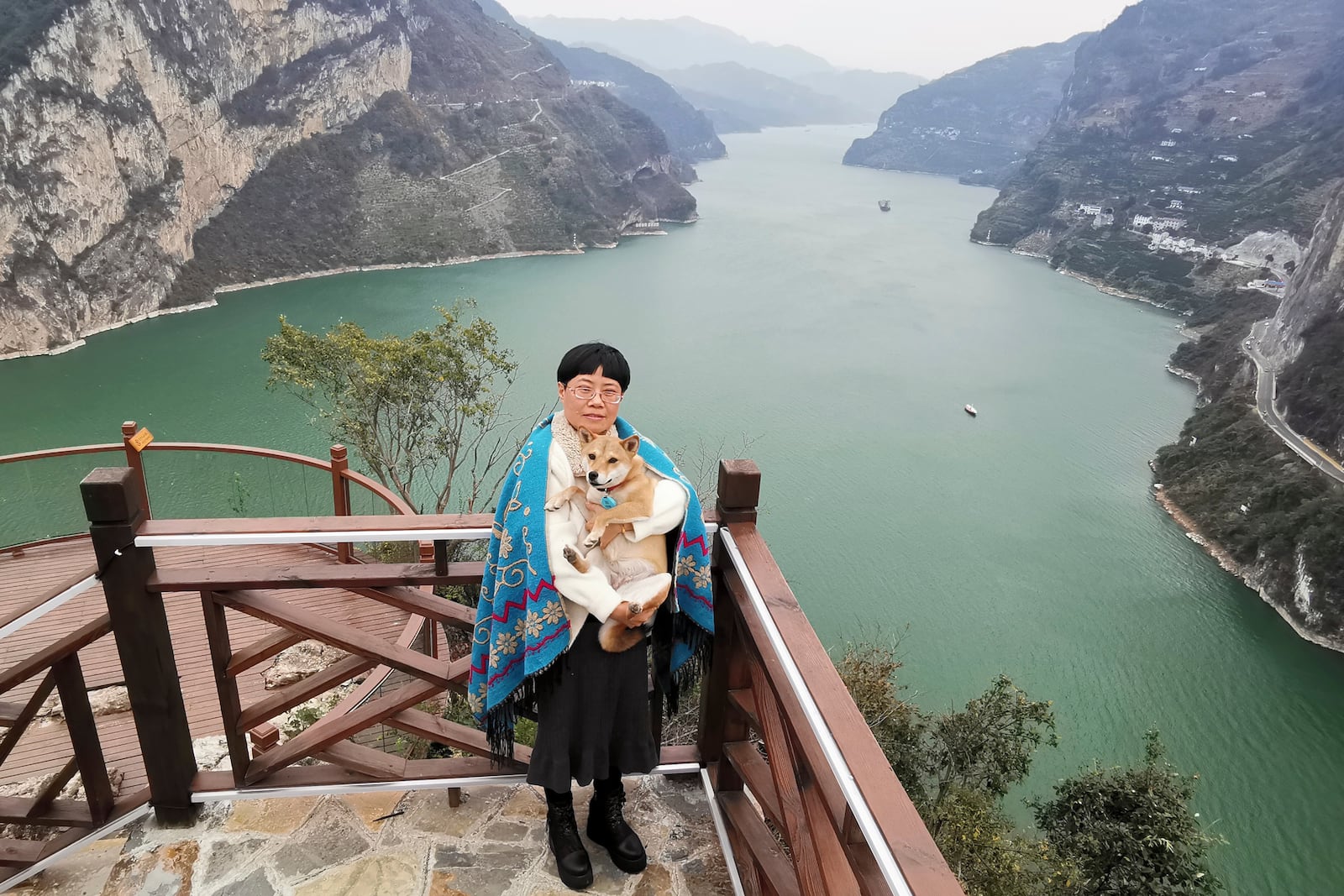 In this photo released by Tan Yuanyi, Zhang Yali poses for photos Dec 8, 2023, with her dog "Little Cotton" near a mountain pass that went viral in China in 2025 as "puppy mountain" in Yichang, a city in central China's Hubei Province. (Tan Yuanyi via AP)