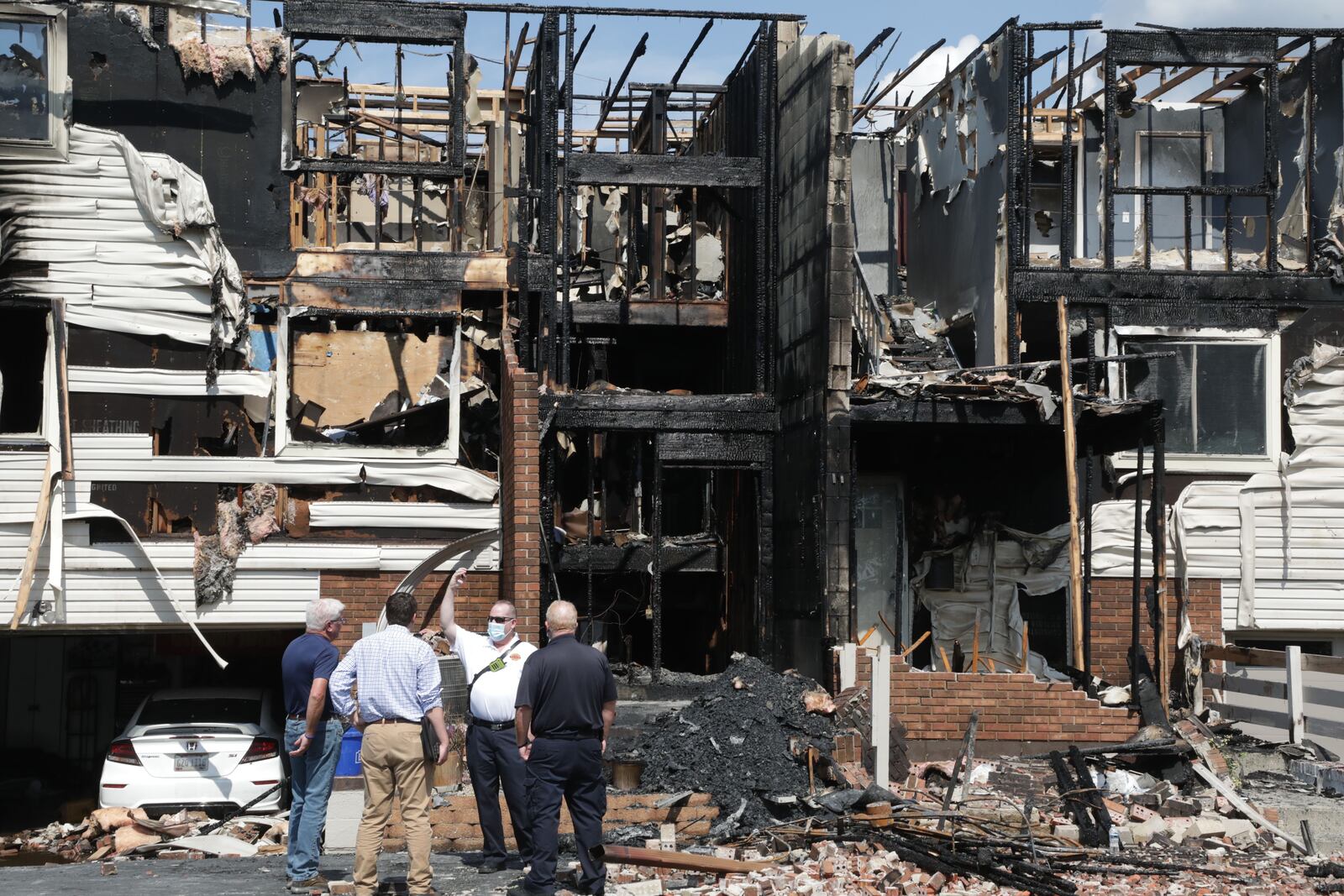 Springfield Assistant Fire Chief Matt Smith talks with insurance investigators about the fire that destroyed six townhouse apartments on Olympic Drive Early Tuesday morning. BILL LACKEY/STAFF