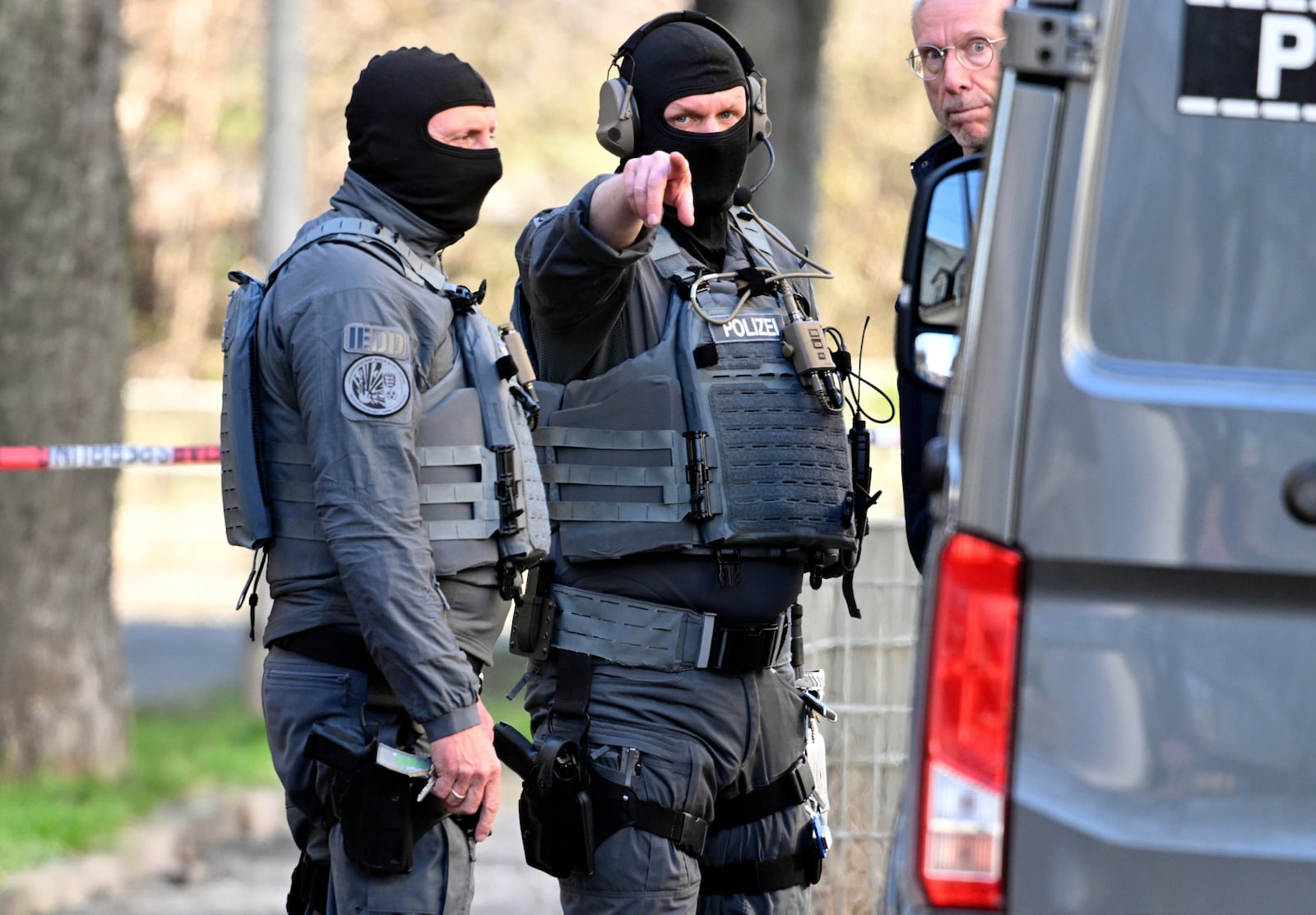 Officers from the police defusing service stand near a damaged vehicle on an access road to the Rhine bridge, in Mannheim, Germany, Monday, March 3, 2025, following an incident when a car rammed into a crowd, German police said. (Boris Roessler/dpa via AP)