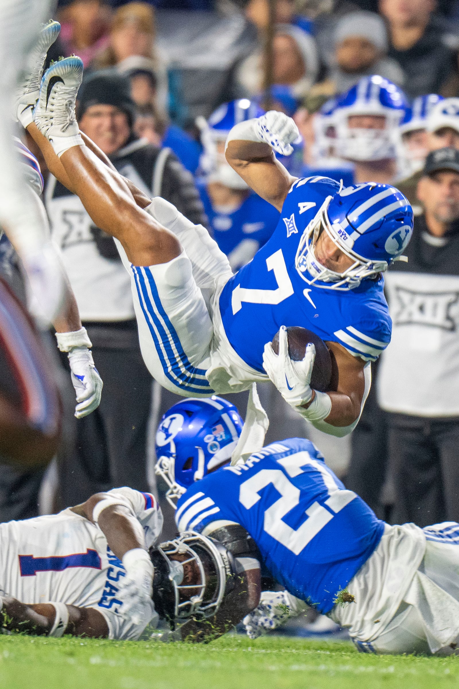 BYU running back Hinckley Ropati (7) is tripped up by Kansas linebacker JB Brown (1) during the first half of an NCAA college football game Saturday, Nov. 16, 2024, in Provo. (AP Photo/Rick Egan)