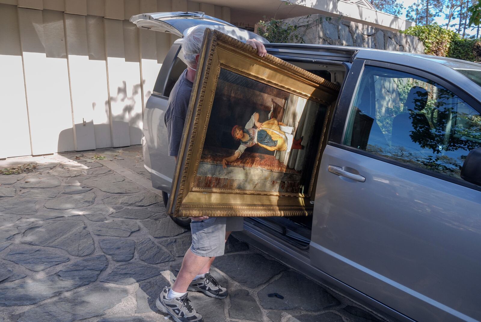 A resident retrieves an oil painting titled "Washer" from a surviving residence in the Pacific Palisades neighborhood of Los Angeles, Friday, Jan. 24, 2025. (AP Photo/Damian Dovarganes)