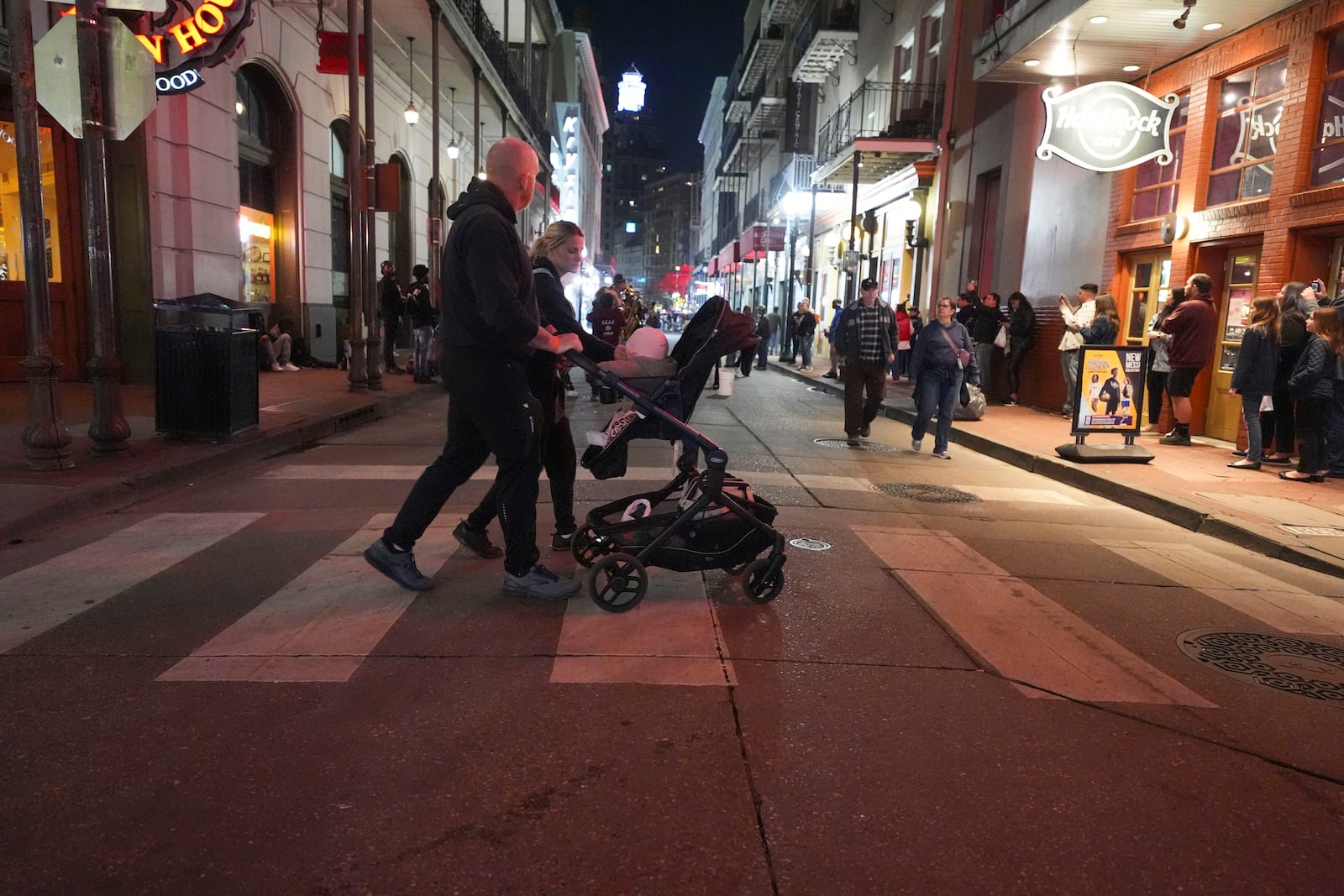 A couple pushes a child in a stroller on Bourbon Street at the site of a deadly truck attack on New Year's Day in New Orleans, Friday, Jan. 3, 2025. (AP Photo/Gerald Herbert)