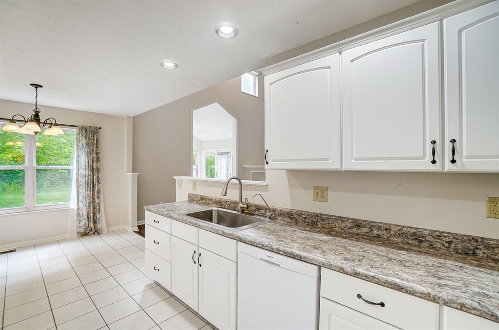 In the kitchen, there is a large sink and a pantry cabinet with pull-out shelves next to the refrigerator nook. 