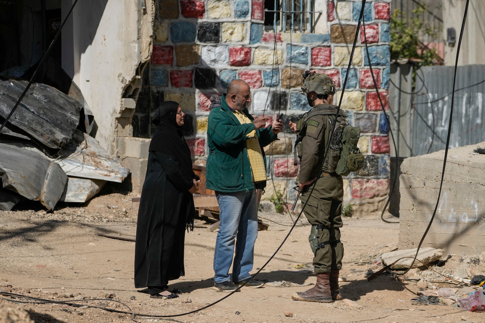 Residents of the West Bank urban refugee camp of Nur Shams speak with an Israeli soldier as the Israeli military continues its operation in the area on Wednesday, Feb. 26, 2025. (AP Photo/Majdi Mohammed)