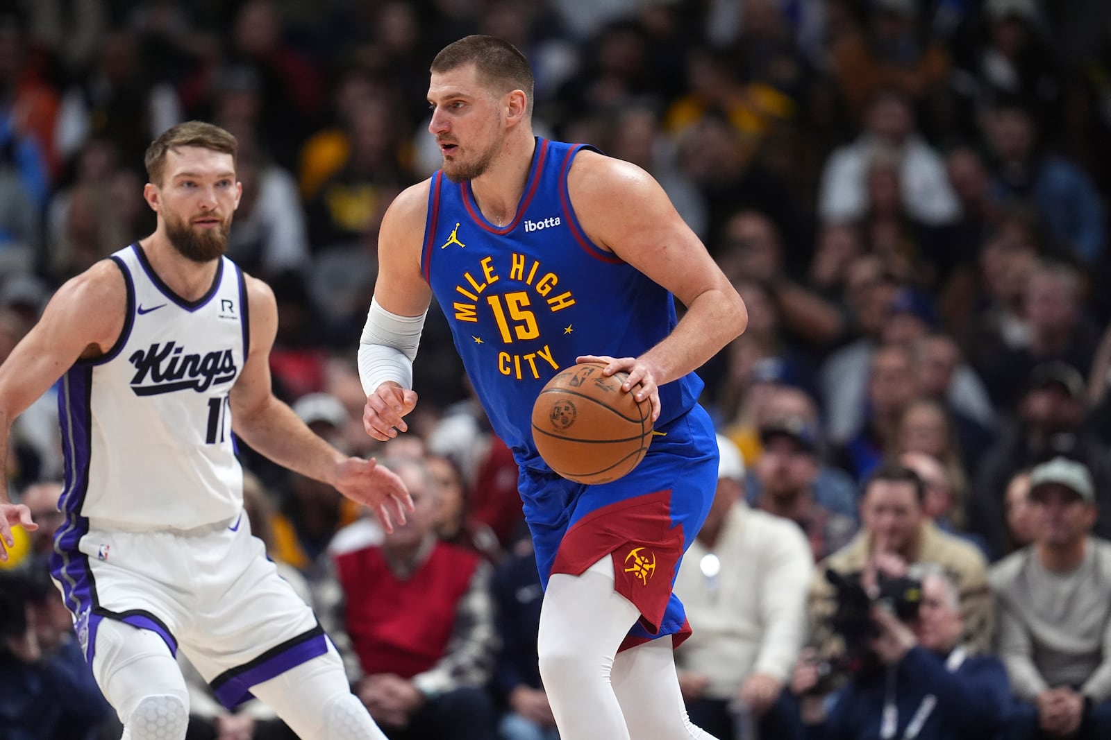 Denver Nuggets center Nikola Jokic, right, looks to pass the ball as Sacramento Kings forward Domantas Sabonis defends in the first half of an NBA basketball game Thursday, Jan. 23, 2025, in Denver. (AP Photo/David Zalubowski)