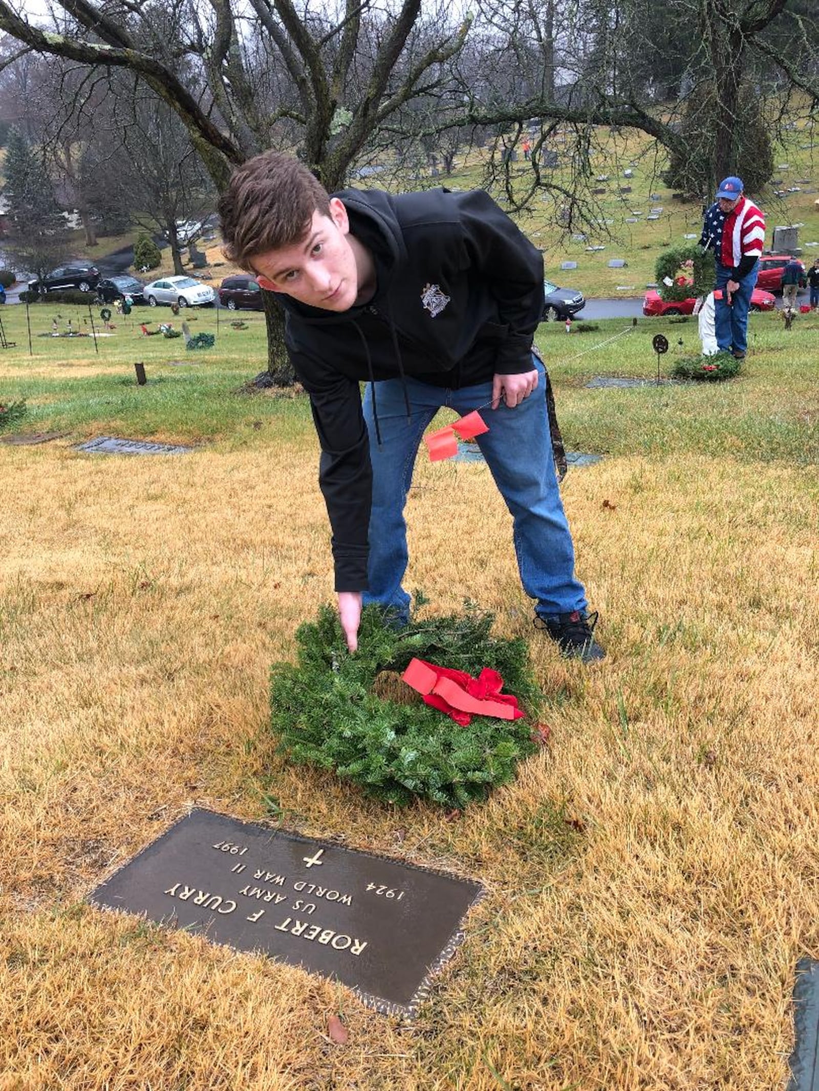 Alex Ackroyd, a Catholic Central High School student, was one of many volunteers who placed wreaths on the graves of nearly 700 U.S. Military veterans interred at St. Benard Cemetry as part of National Wreaths Across America Day. Photo by Brett Turner