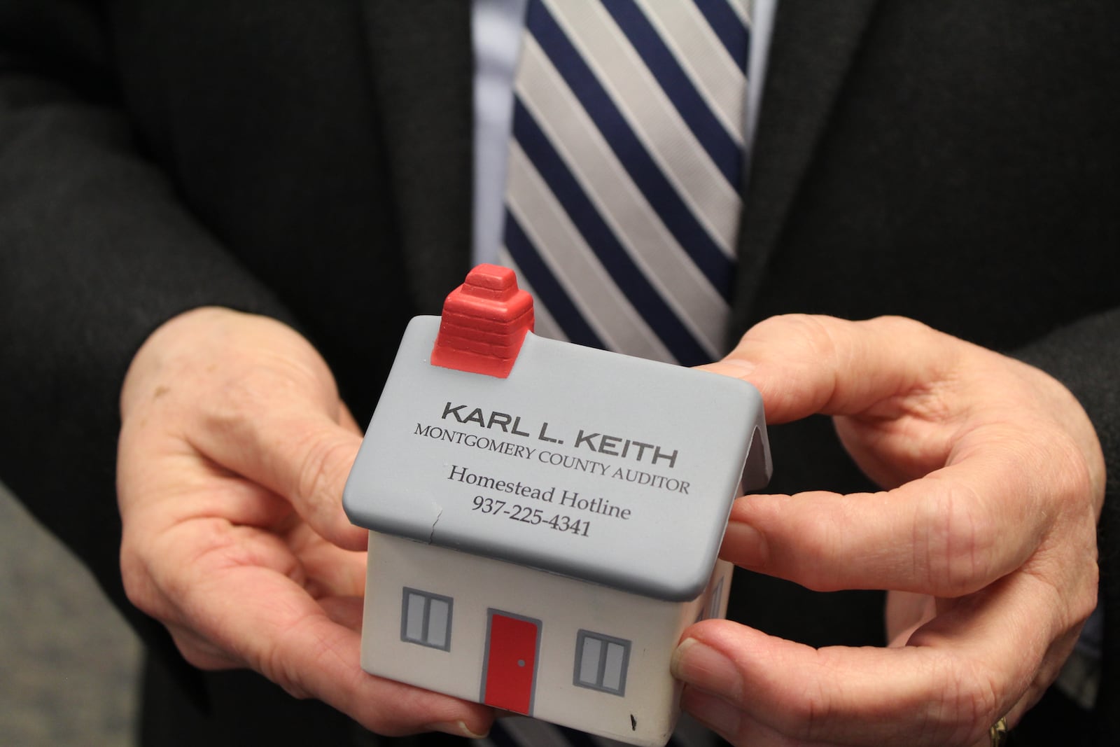 Montgomery County Auditor Karl Keith holds a foam desktop toy with the phone number citizens can call to learn more about the homestead exemption program. CORNELIUS FROLIK / STAFF