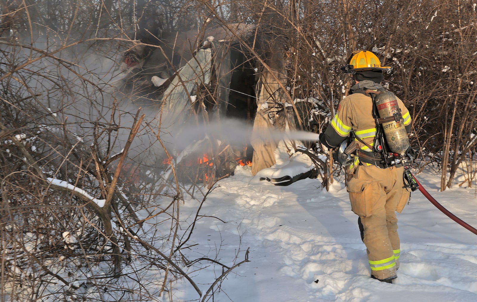 A Member of the Springfield Fire & Rescue Division extinguishes a fire at a homeless encampment along East High Street Thursday, Jan. 9, 2025. The residents of the encampment were not present when the fire department arrived. BILL LACKEY/STAFF