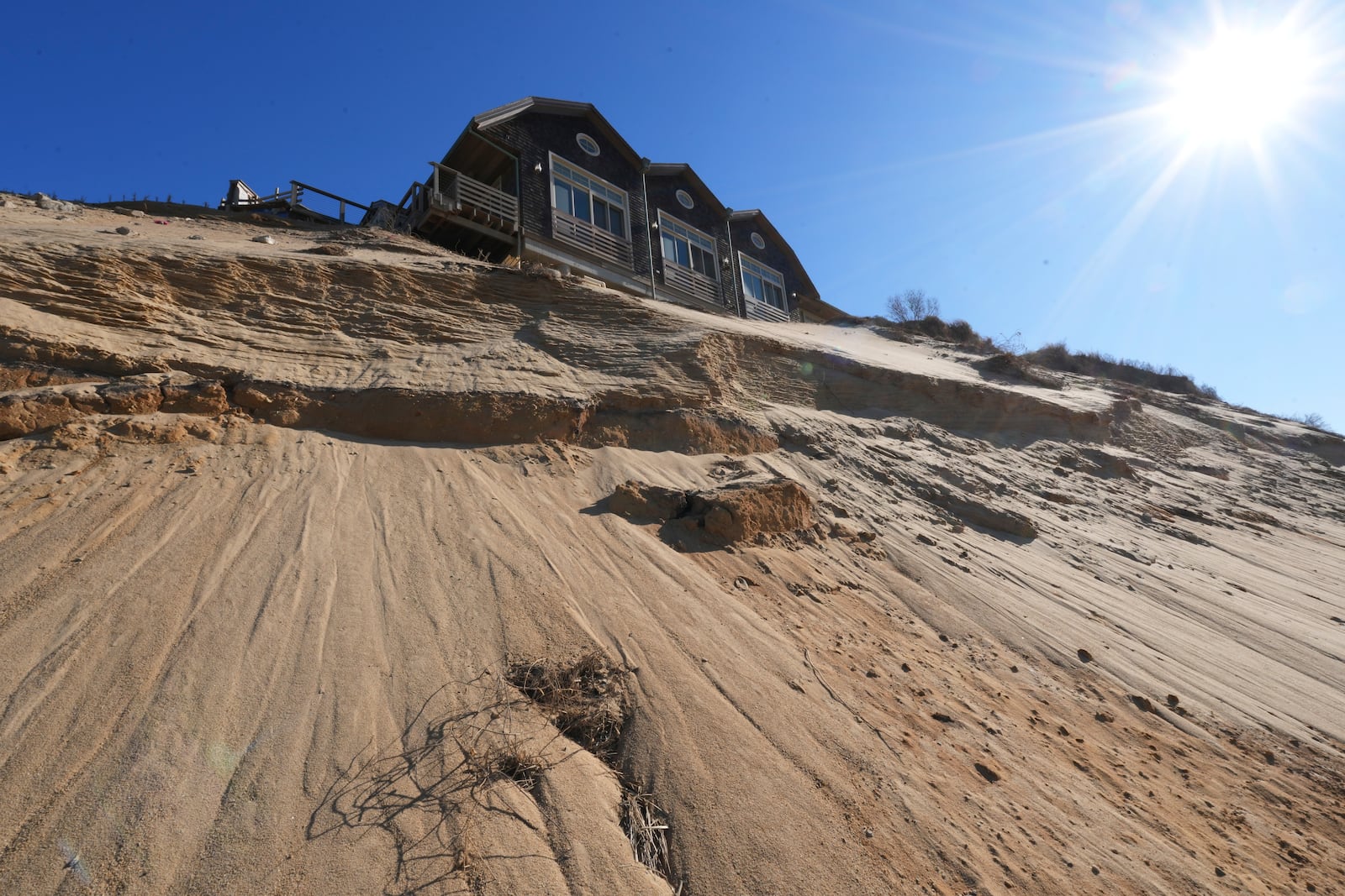 A home sits atop of a sandy bluff overlooking a beach in Wellfleet, Mass., Monday, Jan. 27, 2025. (AP Photo/Andre Muggiati)