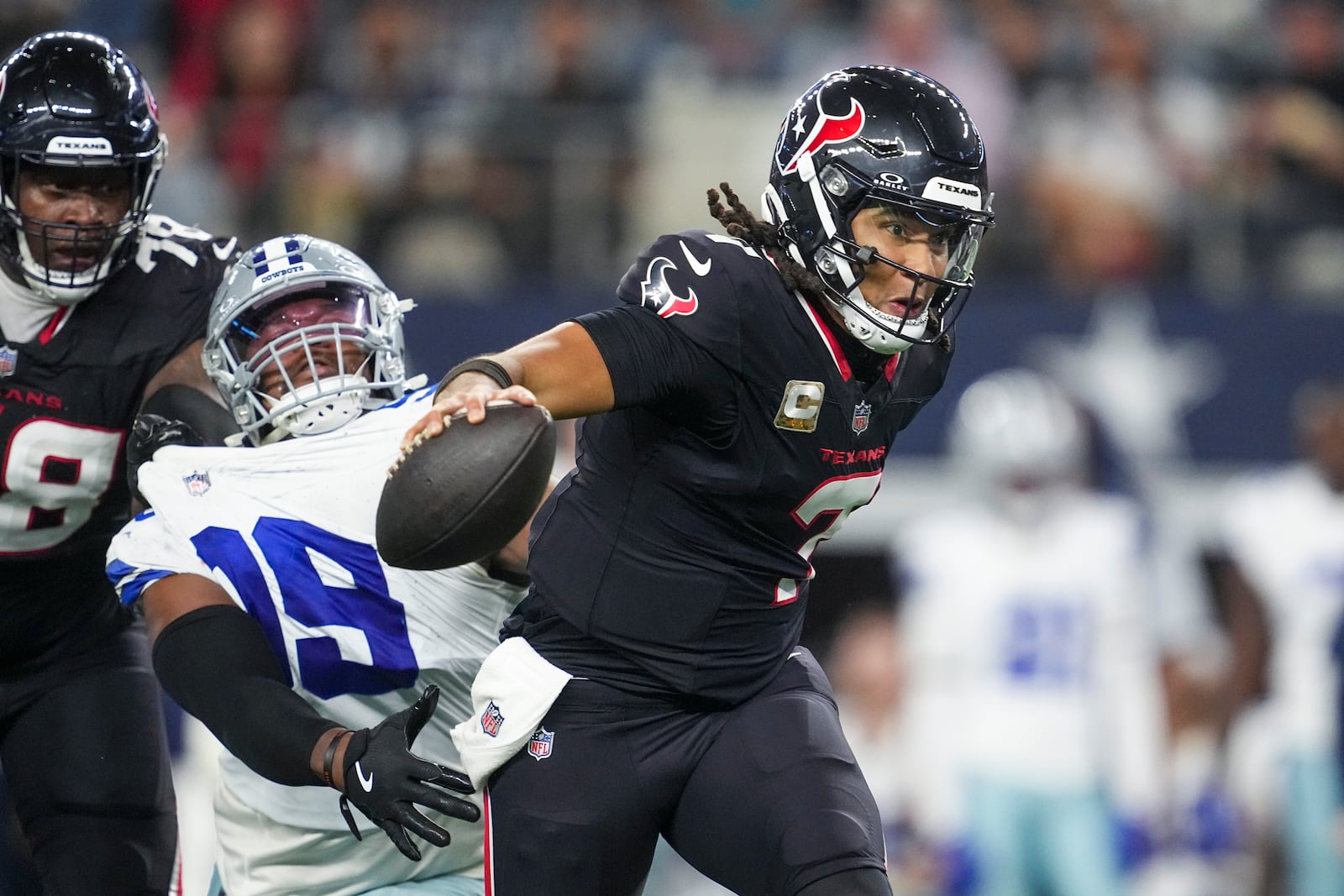 Houston Texans quarterback C.J. Stroud, right, gets help from offensive tackle Laremy Tunsil, left, to escape a tackle attempt by Dallas Cowboys quarterback Trey Lance during the second half of an NFL football game, Monday, Nov. 18, 2024, in Arlington, Texas. (AP Photo/Tony Gutierrez)