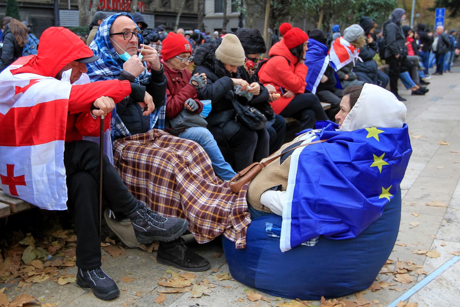 Protesters with EU and Georgian national flags rest in a street during a rally to demand new parliamentary elections in the country, near the Parliament's building in Tbilisi, Georgia, on Monday, Nov. 25, 2024. (AP Photo/Shakh Aivazov)