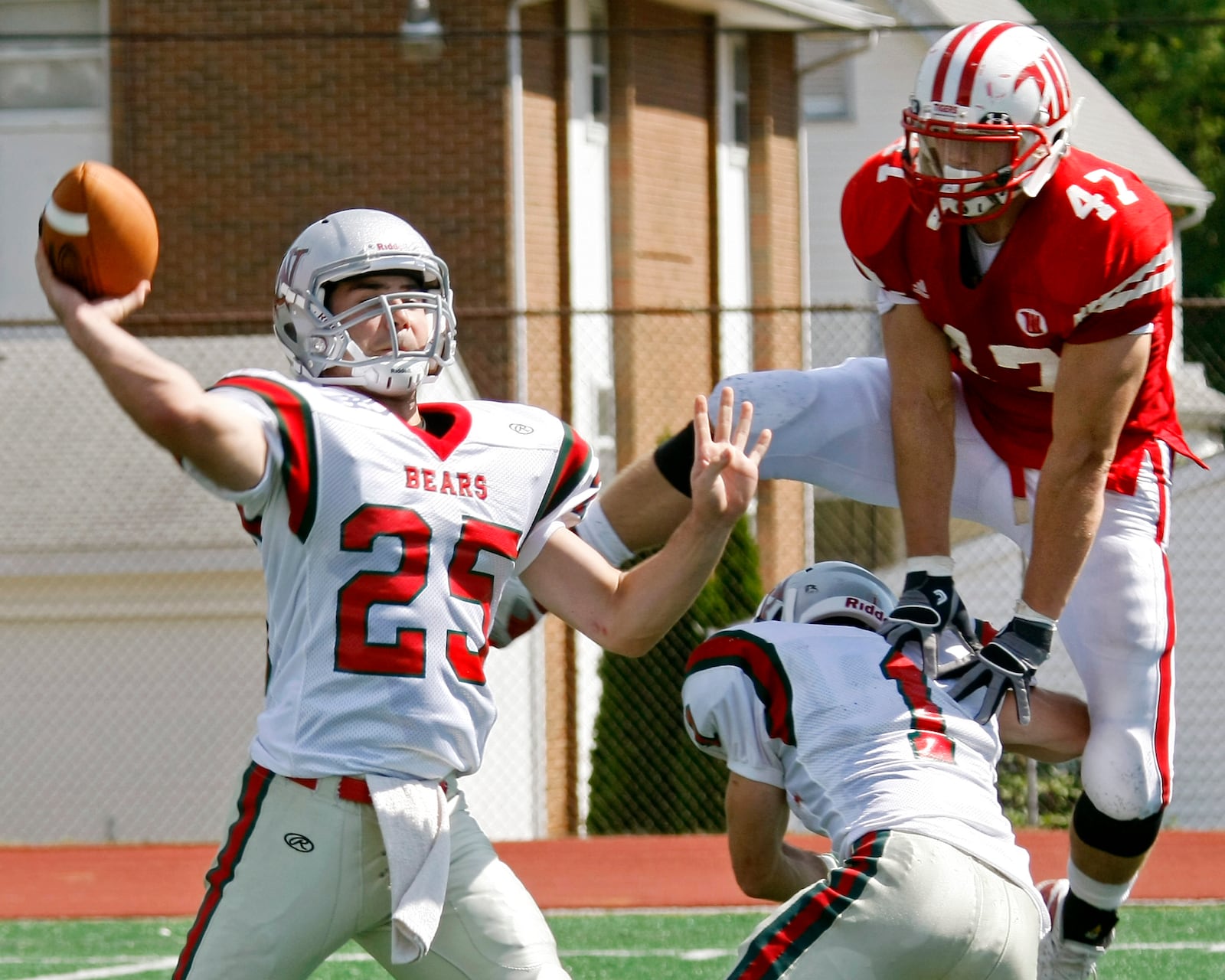 Eddie Vallery (47) of Wittenberg hurdles Jim O'Brien (1) of Washington in attempt to get to quarterback Stephen Sherman (25) during Saturday's game at Edwards-Maurer Field on Sept. 18, 2010. Witteneberg won the game 37-7.