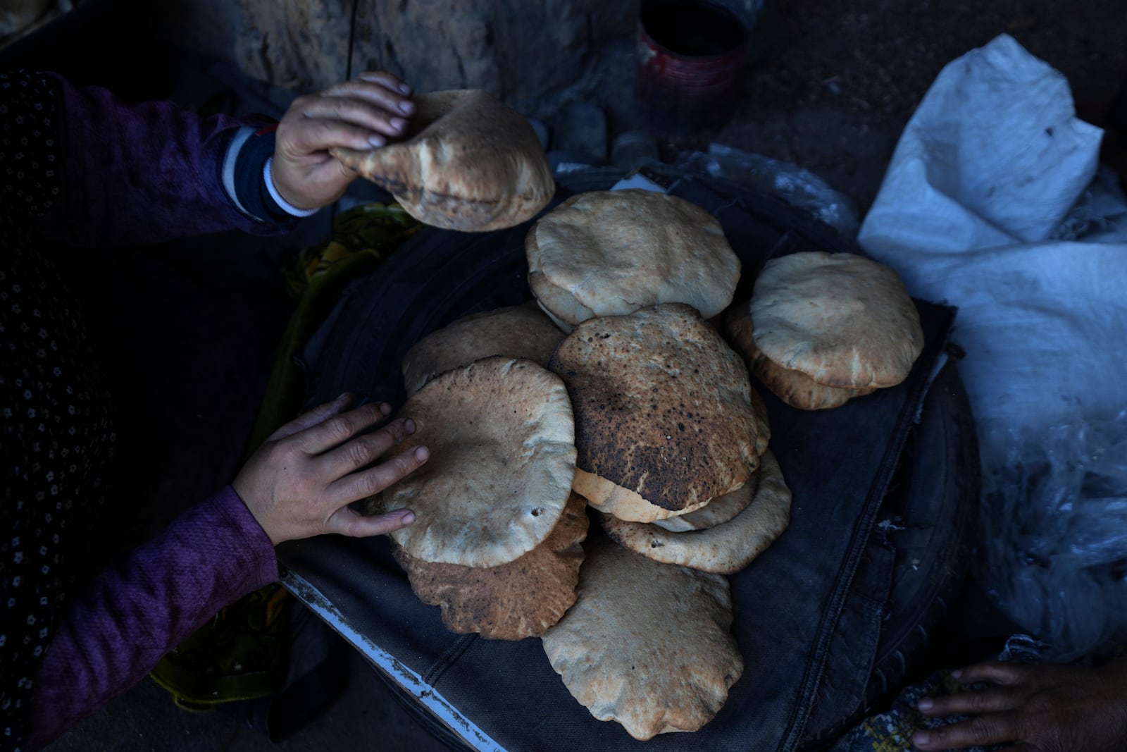 A Palestinian woman sorts through fresh bread amid dire food shortages in Deir al-Balah, Gaza Strip, Monday, Dec. 2, 2024. (AP Photo/Abdel Kareem Hana)