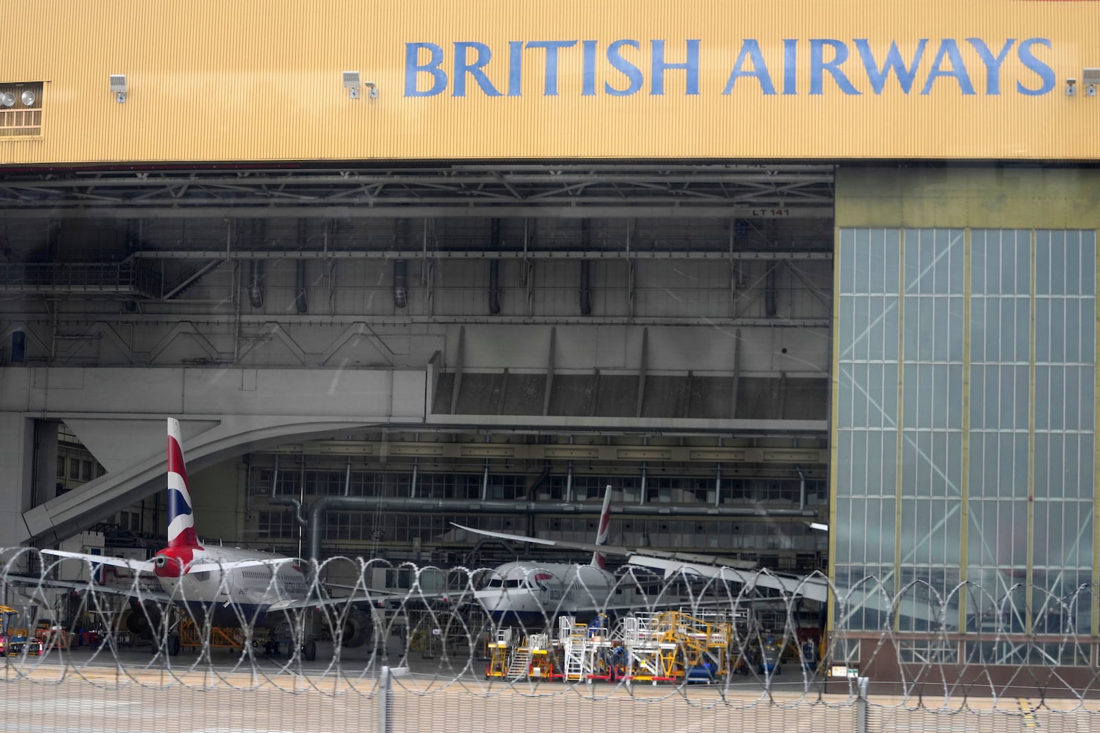 British Airways planes are sitting in a hangar as Britain's Heathrow Airport has closed for the full day Friday after an electrical substation fire knocked out its power, disrupting flights for hundreds of thousands of passengers at one of Europe's biggest travel hubs in London, Friday, March 21, 2025.(AP Photo/Kin Cheung)