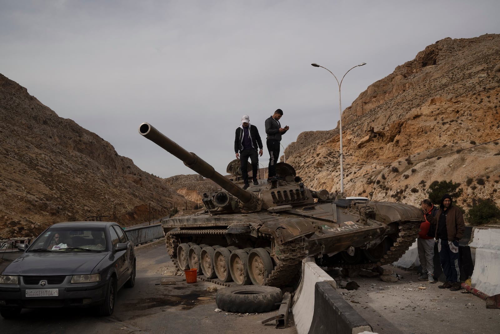 Syrians stand on the top of a government forces tank that was left on a road, on their way to Damascus, Syria, Wednesday, Dec. 11, 2024. (AP Photo/Leo Correa)