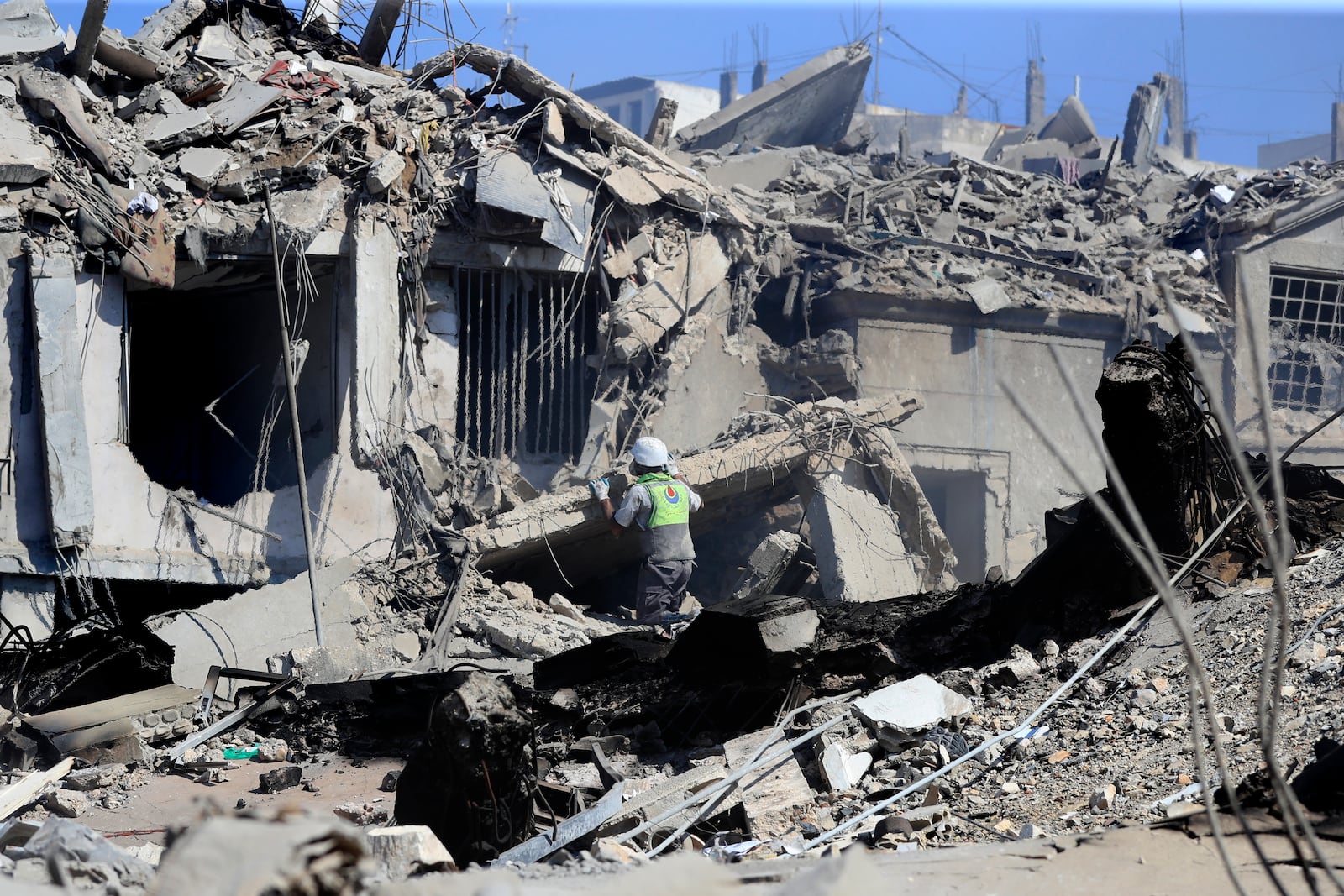 A Hezbollah rescue worker searches for victims amidst the rubble of destroyed buildings at a commercial street that was hit Saturday night by Israeli airstrikes, in Nabatiyeh town, south Lebanon, Sunday, Oct. 13, 2024. (AP Photo/Mohammed Zaatari)