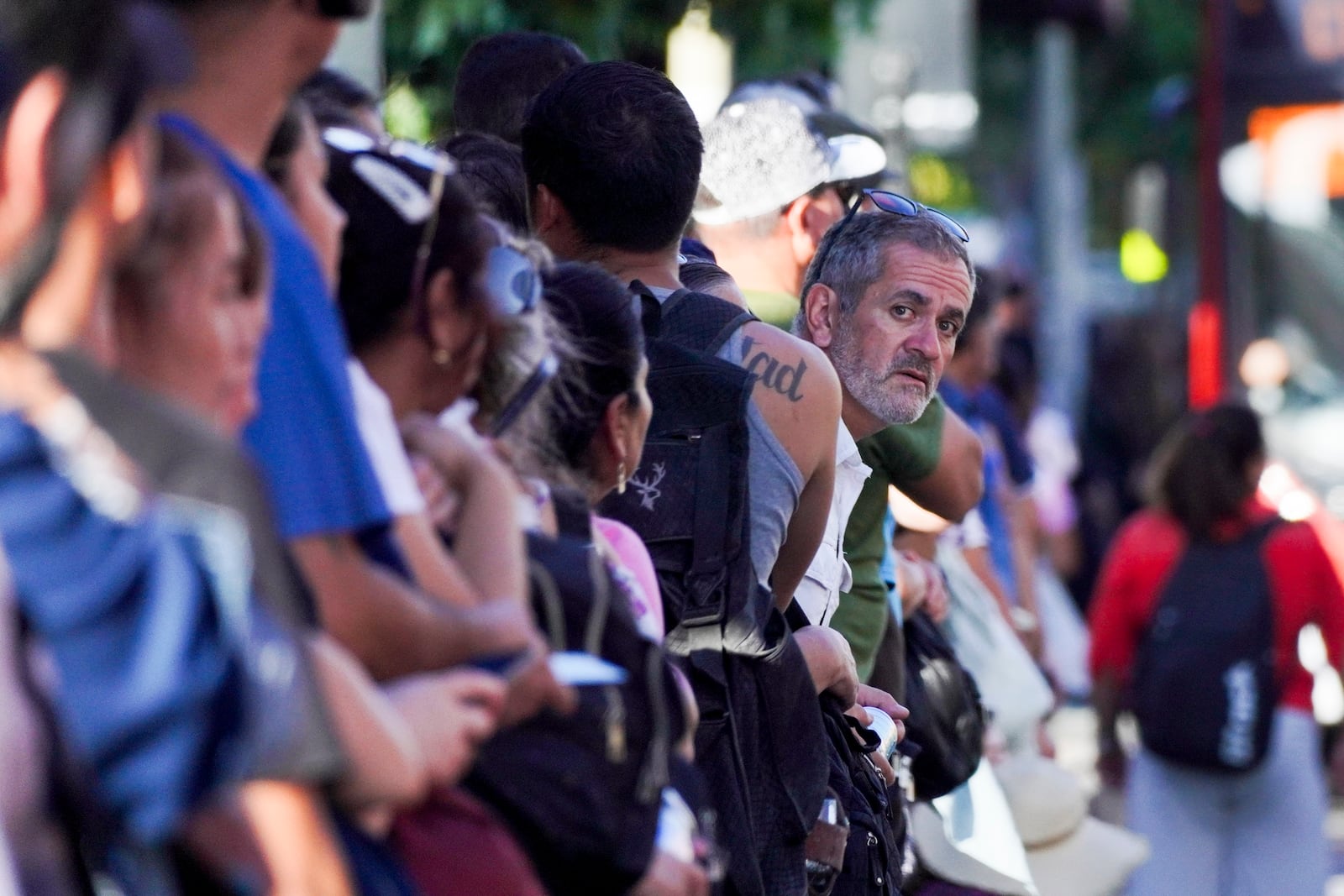 People wait in line at a bus stop during a power outage that has left the city without subway service in Santiago, Chile, Tuesday, Feb. 25, 2025. (AP Photo/Matias Basualdo)