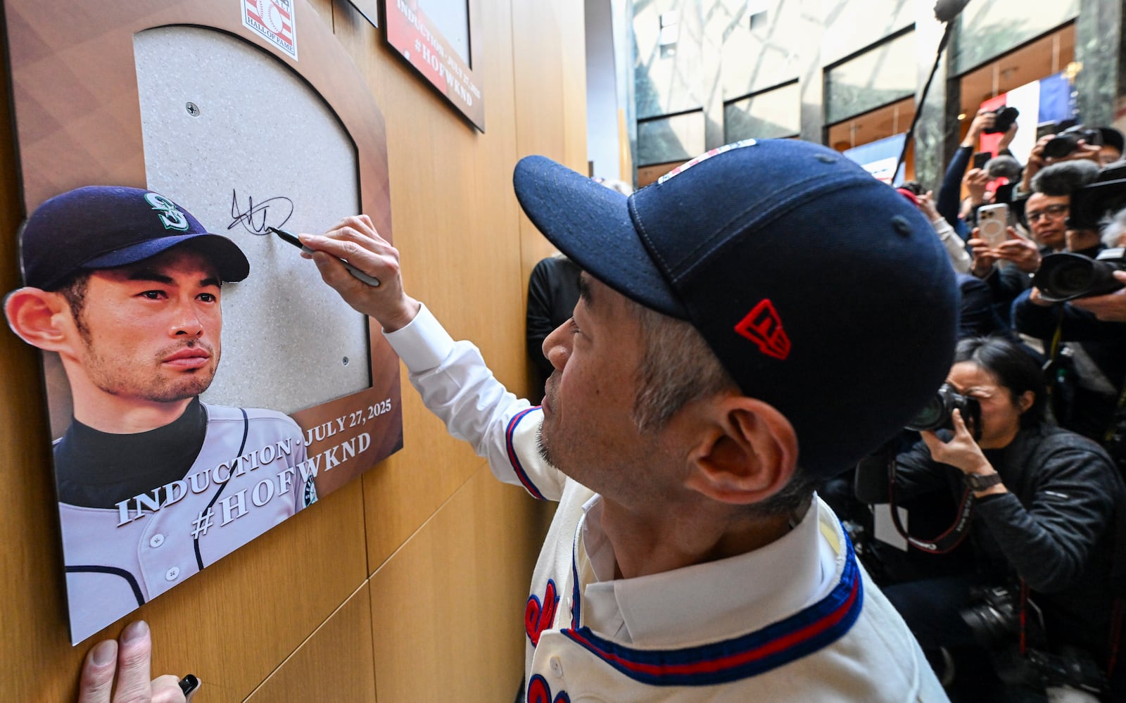 Newly-elected Baseball Hall of Fame member Ichiro Suzuki signs the backer board where his plaque will hang during a news conference Thursday, Jan. 23, 2025, in Cooperstown, N.Y. (AP Photo/Hans Pennink)