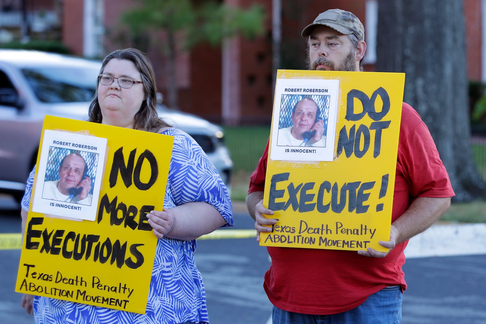 Jennifer Martin, left, and Thomas Roberson, older brother of condemned prisoner Robert Roberson, right, holds signs as they protest outside the prison where Roberson is scheduled for execution at the Huntsville Unit of the Texas State Penitentiary, Thursday, Oct. 17, 2024, in Huntsville, Texas. (AP Photo/Michael Wyke)