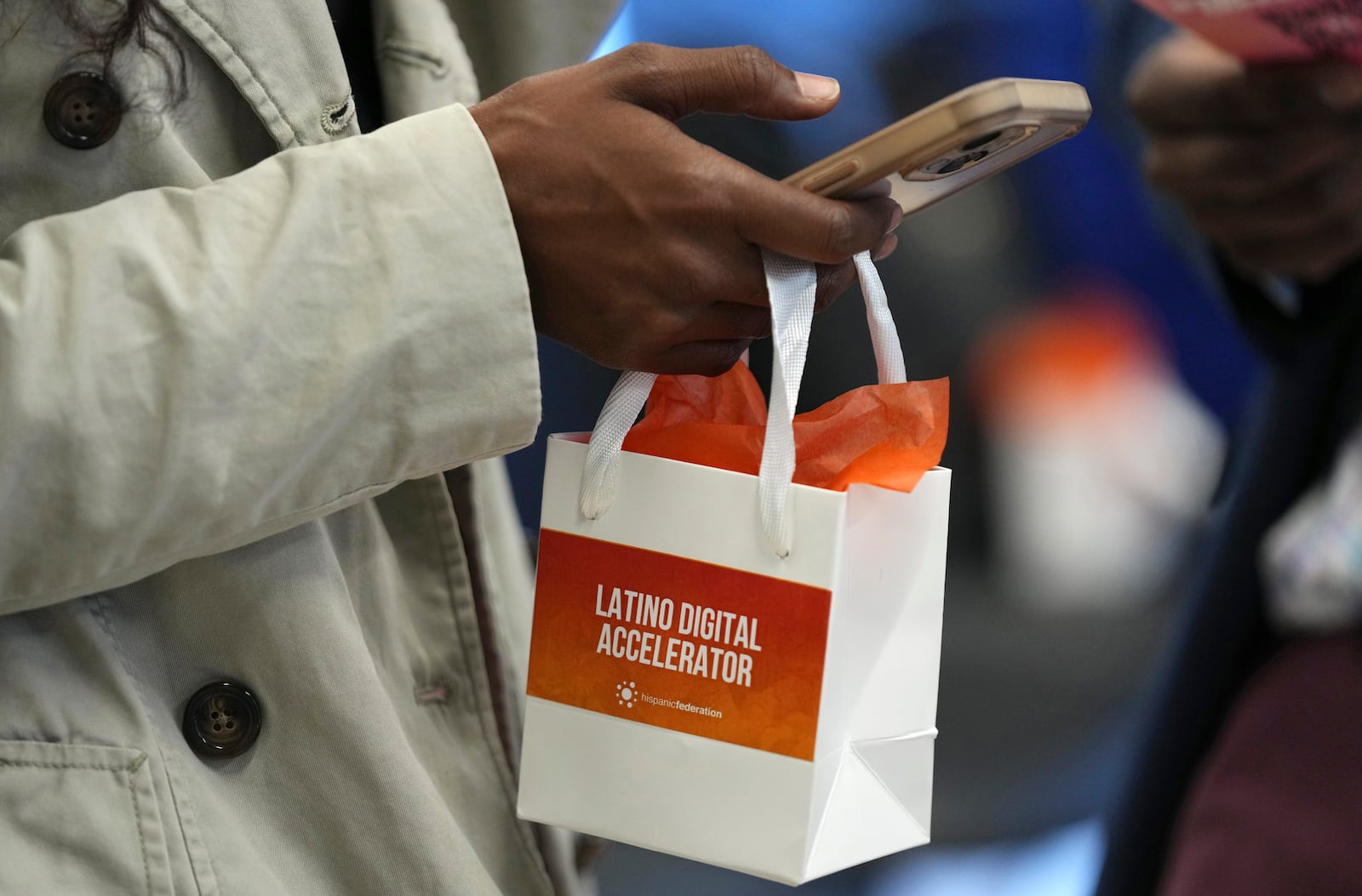 An attendee holds a gift bag at a Hispanic Federation event in Miami, Tuesday, Jan. 28, 2025, where the organization announced a new investment from a company, to help Latinos learn digital skills. (AP Photo/Lynne Sladky)