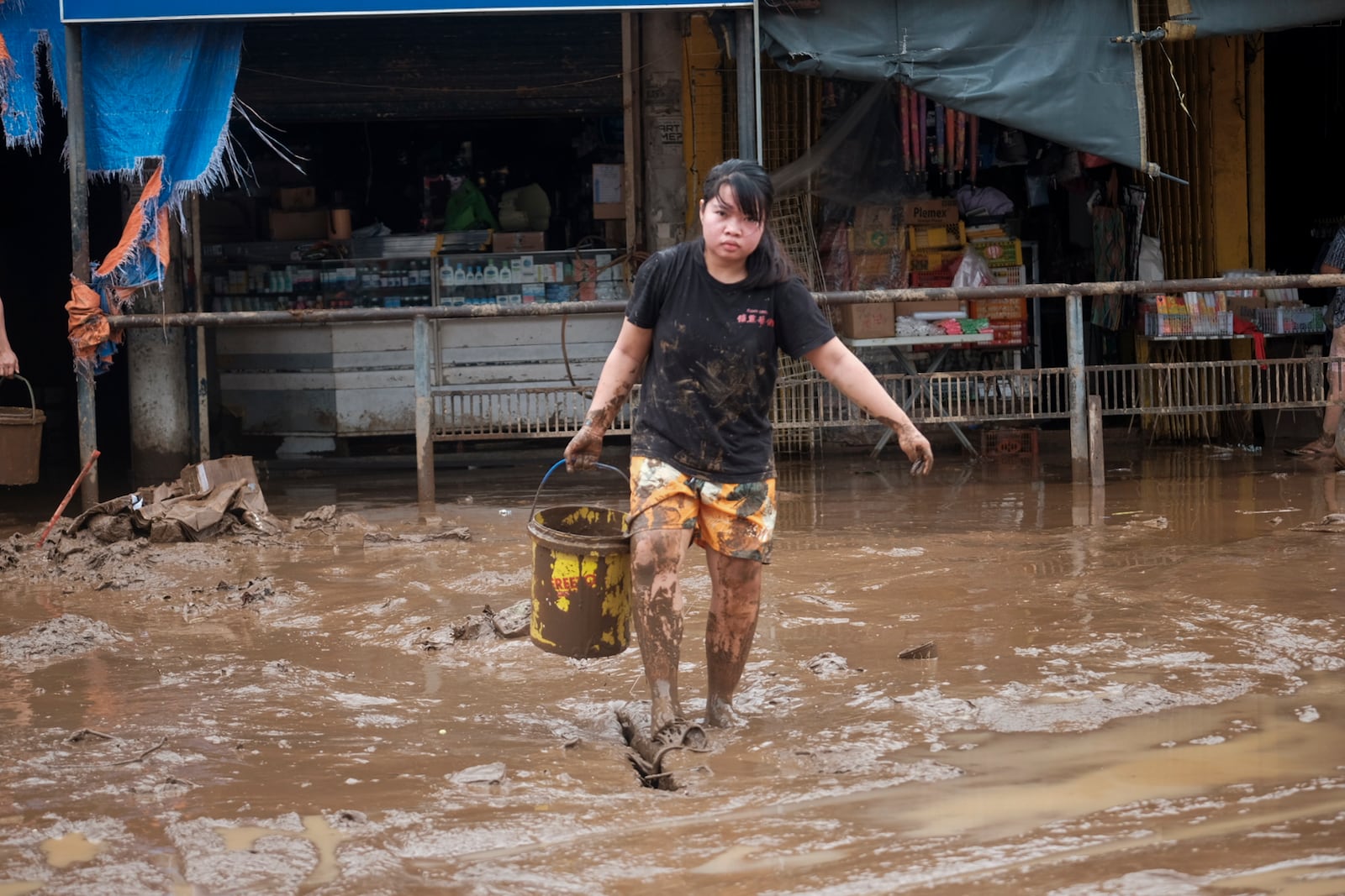 A resident collects mud as they start cleaning their area after floods caused by Tropical Trami, locally named Kristine, in Polangui, Albay province, Philippines on Oct. 23, 2024. (AP Photo/John Michael Magdasoc)