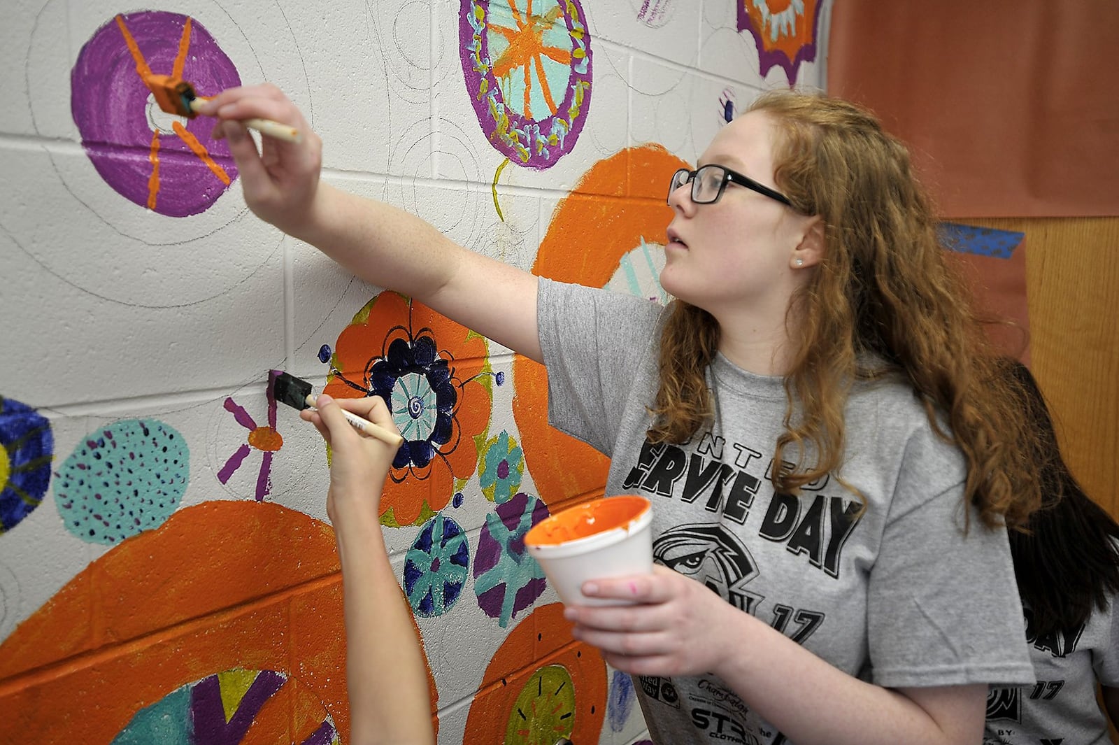 Graham Middle School students, including Paris Long, paint a mural on one of the walls of the school Friday for Service Day.