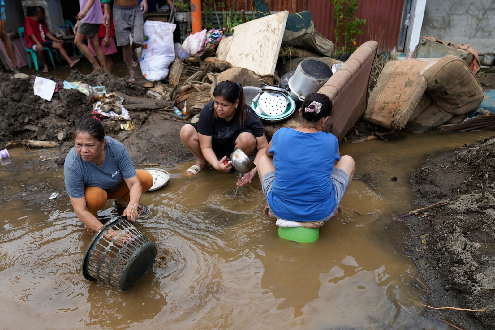 Residents try to clear out mud from their belongings after a landslide triggered by Tropical Storm Trami recently struck Talisay, Batangas province, Philippines, Saturday, Oct. 26, 2024. (AP Photo/Aaron Favila)