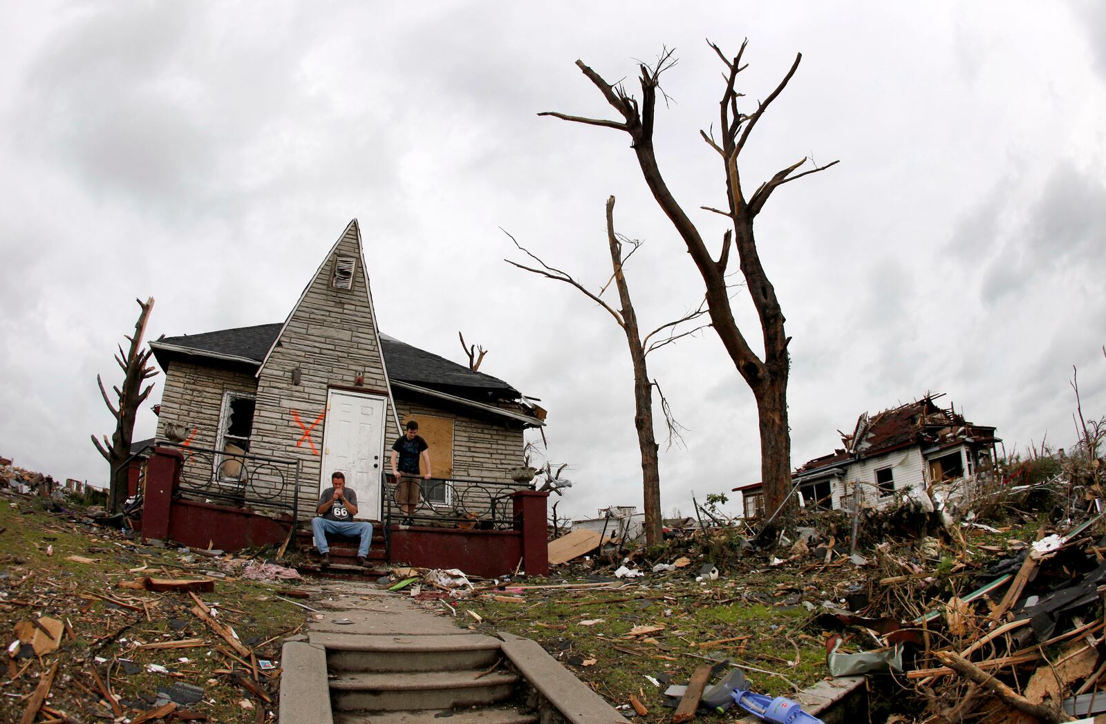 FILE- Bruce Hawkins, sitting, and his stepson James Hurst take a break from clean up at his moderately damaged home in a heavily devastated Joplin neighborhood Wednesday, May 25, 2011. (AP Photo/Charlie Riedel, File)