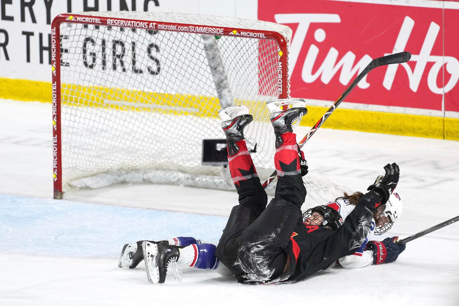 Canada's Laura Stacey, left, celebrates her empty-net goal while falling into Team USA's Kelly Pannek during the third period of Rivalry Series hockey action in Summerside, Prince Edward Island, Canada, Saturday, Feb. 8, 2025. (Darren Calabrese/The Canadian Press via AP)