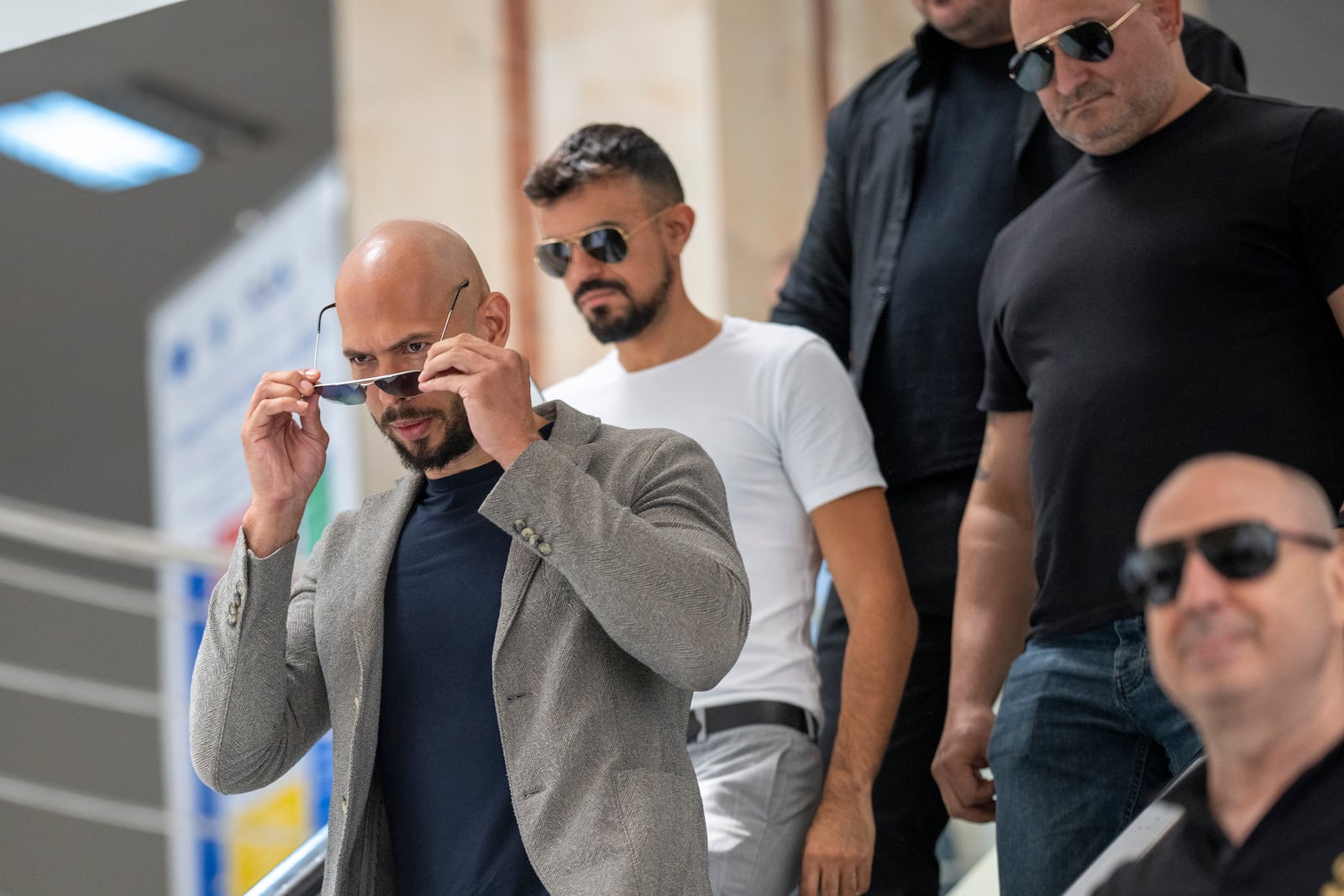 Andrew Tate leaves the Bucharest Tribunal along with his bodyguards after the first hearing his trial, meant to establish if he and his brother Tristan will remain under house arrest, in Bucharest, Romania, Wednesday, June 21, 2023. Romanian prosecutors charged on Tuesday, June 20, 2023, the Tate brothers and two other suspects with human trafficking, rape and organizing a criminal group for the sexual exploitation of women. (AP Photo/Vadim Ghirda)