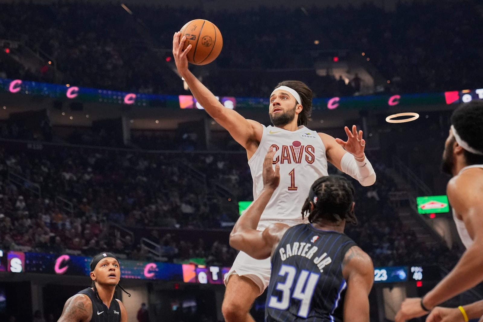 Cleveland Cavaliers guard Max Strus (1) goes up for a shot between Orlando Magic forward Paolo Banchero, left, and center Wendell Carter Jr. (34) in the first half of an NBA basketball game Sunday, March 16, 2025, in Cleveland. (AP Photo/Sue Ogrocki)