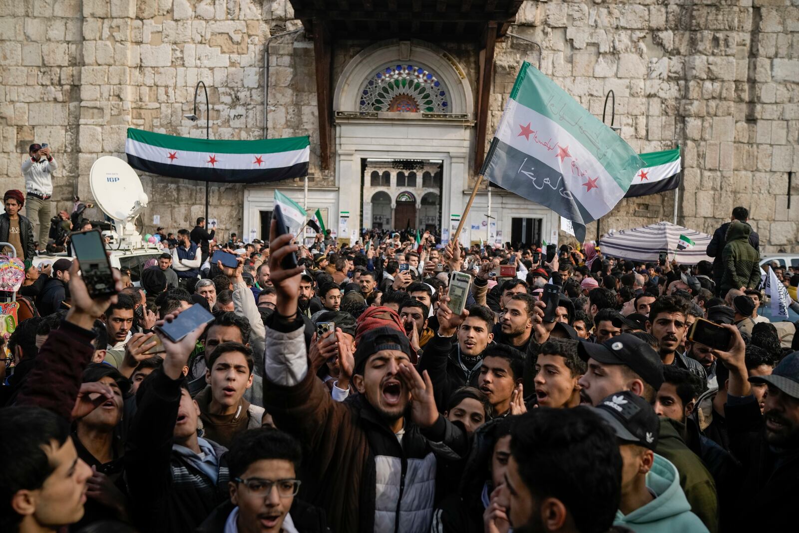 A man shouts as others wave Syrian 'revolutionary' flags in celebration after Friday prayers at the Umayyad Mosque, in Damascus, Syria, Friday, Dec. 20, 2024. (AP Photo/Leo Correa)