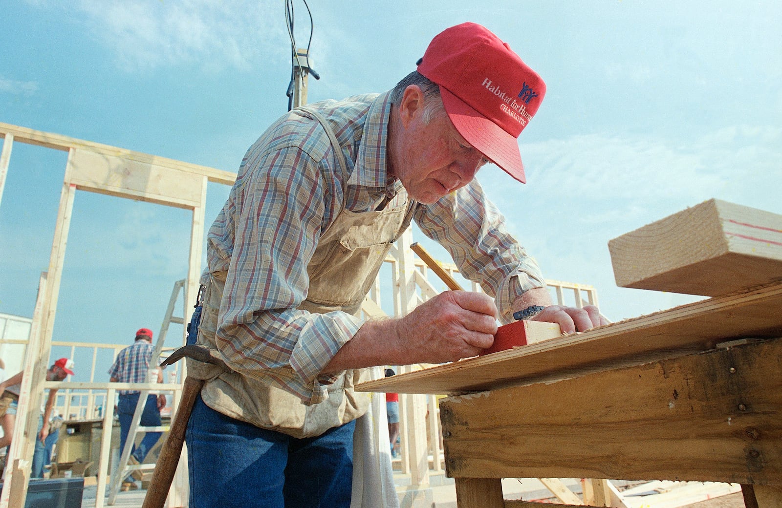 Former Pres. Jimmy Carter marks a board to be cut as he works with the Habitat for Humanity project in Charlotte, N.C., on Monday, July 27, 1987. The group of workers plans to build 14 homes in five days. (AP Photo/Mark Humphrey)