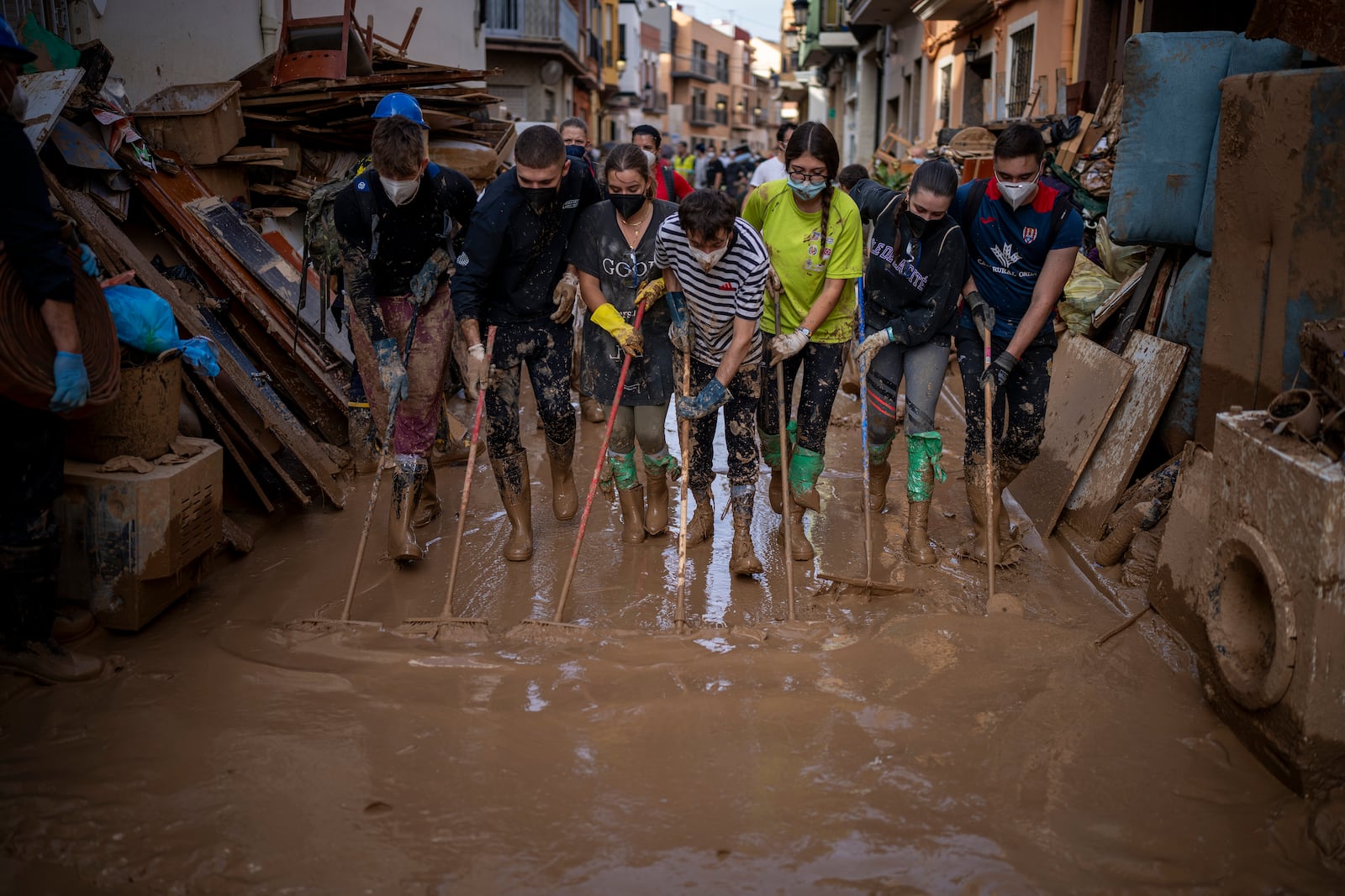 Volunteers and residents clean the mud from the streets in an area affected by floods in Paiporta, Valencia, Spain, Tuesday, Nov. 5, 2024. (AP Photo/Emilio Morenatti)