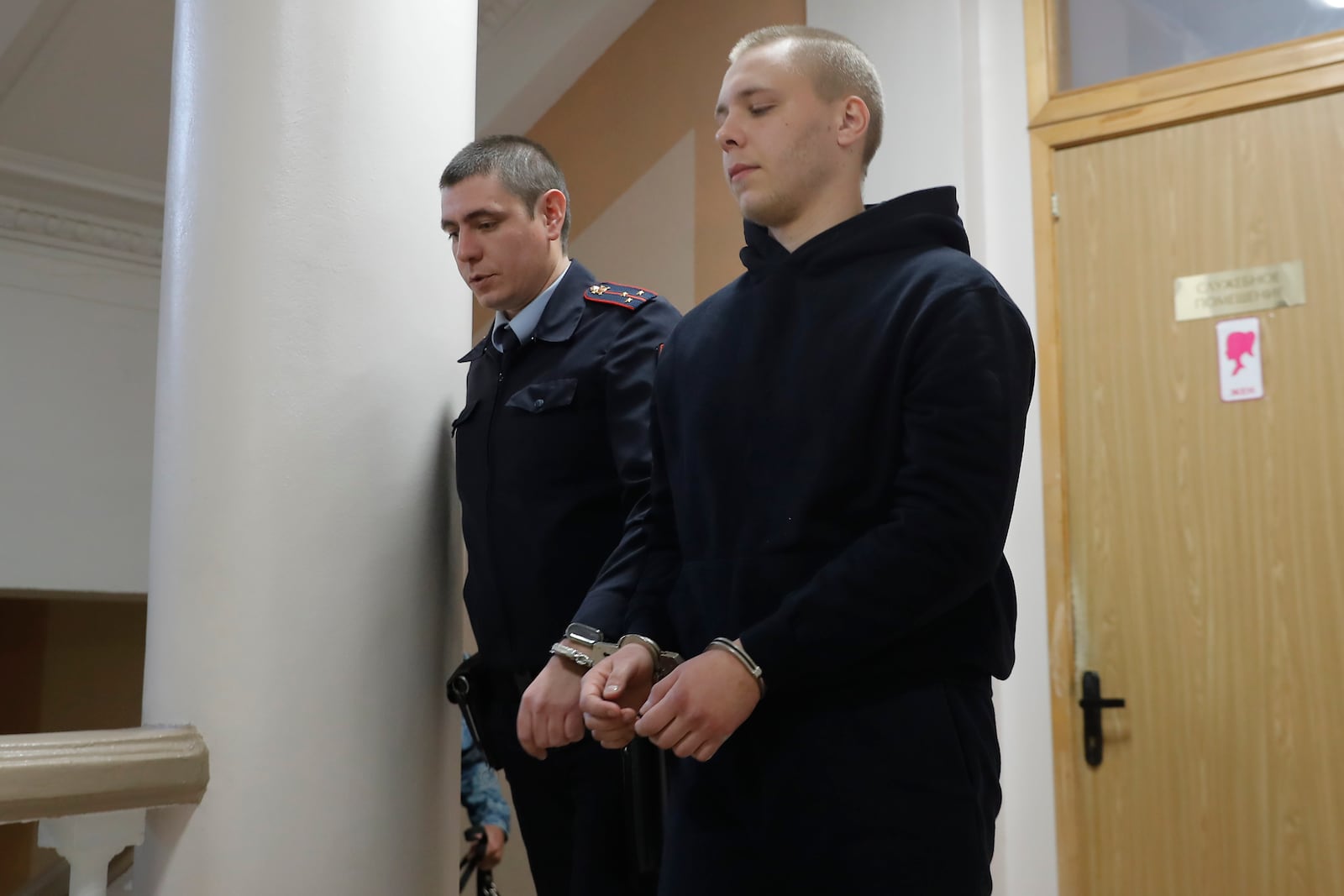 Nikita Zhuravel, right, is escorted by the police to a courtroom prior to a hearing of a treason case in Volgograd, Russia, Thursday, Nov. 14, 2024. (AP Photo)