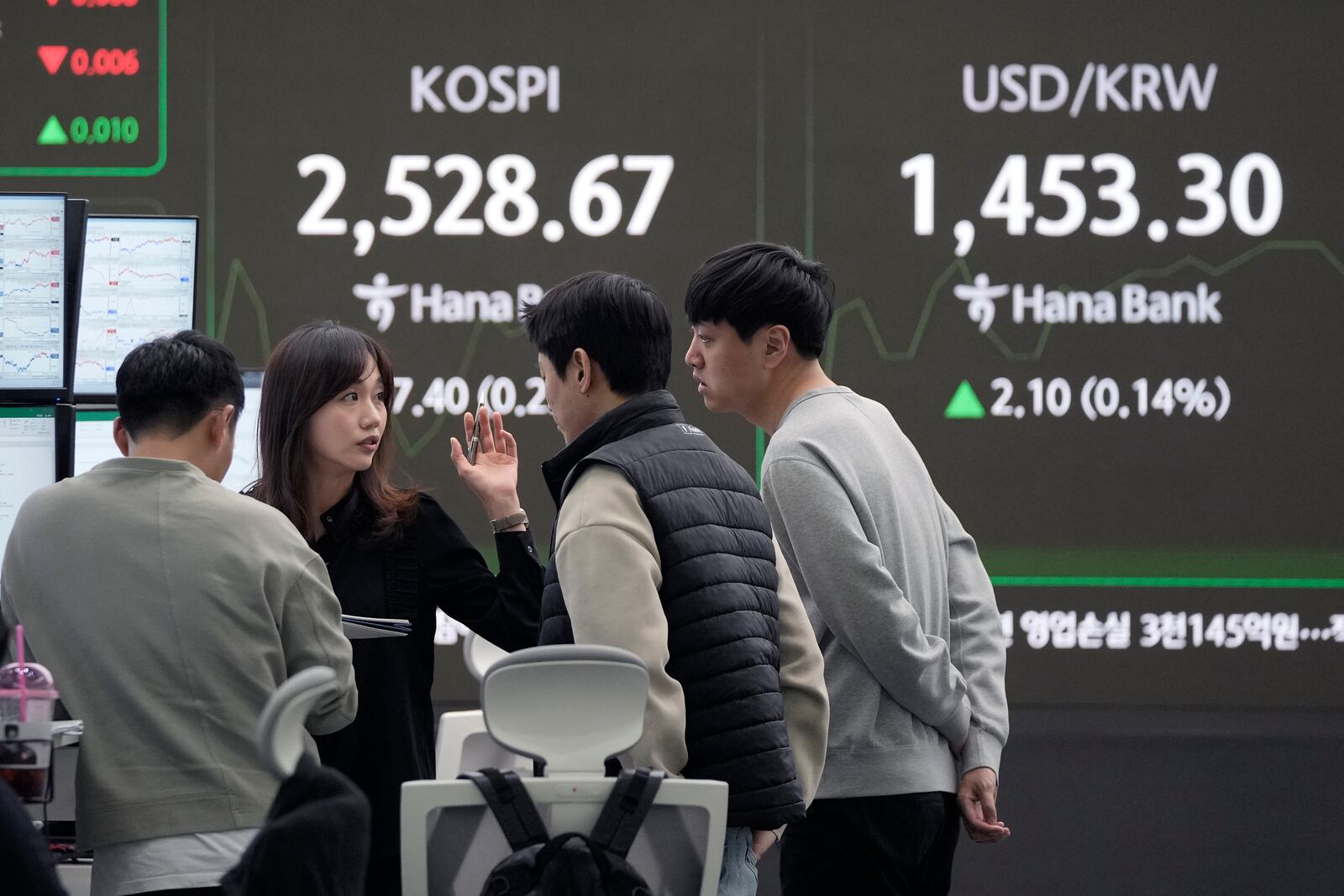 Currency traders work near a screen showing the Korea Composite Stock Price Index (KOSPI) and the foreign exchange rate between U.S. dollar and South Korean won, top right, at the foreign exchange dealing room of the KEB Hana Bank headquarters in Seoul, South Korea, Tuesday, Feb. 11, 2025. (AP Photo/Ahn Young-joon)