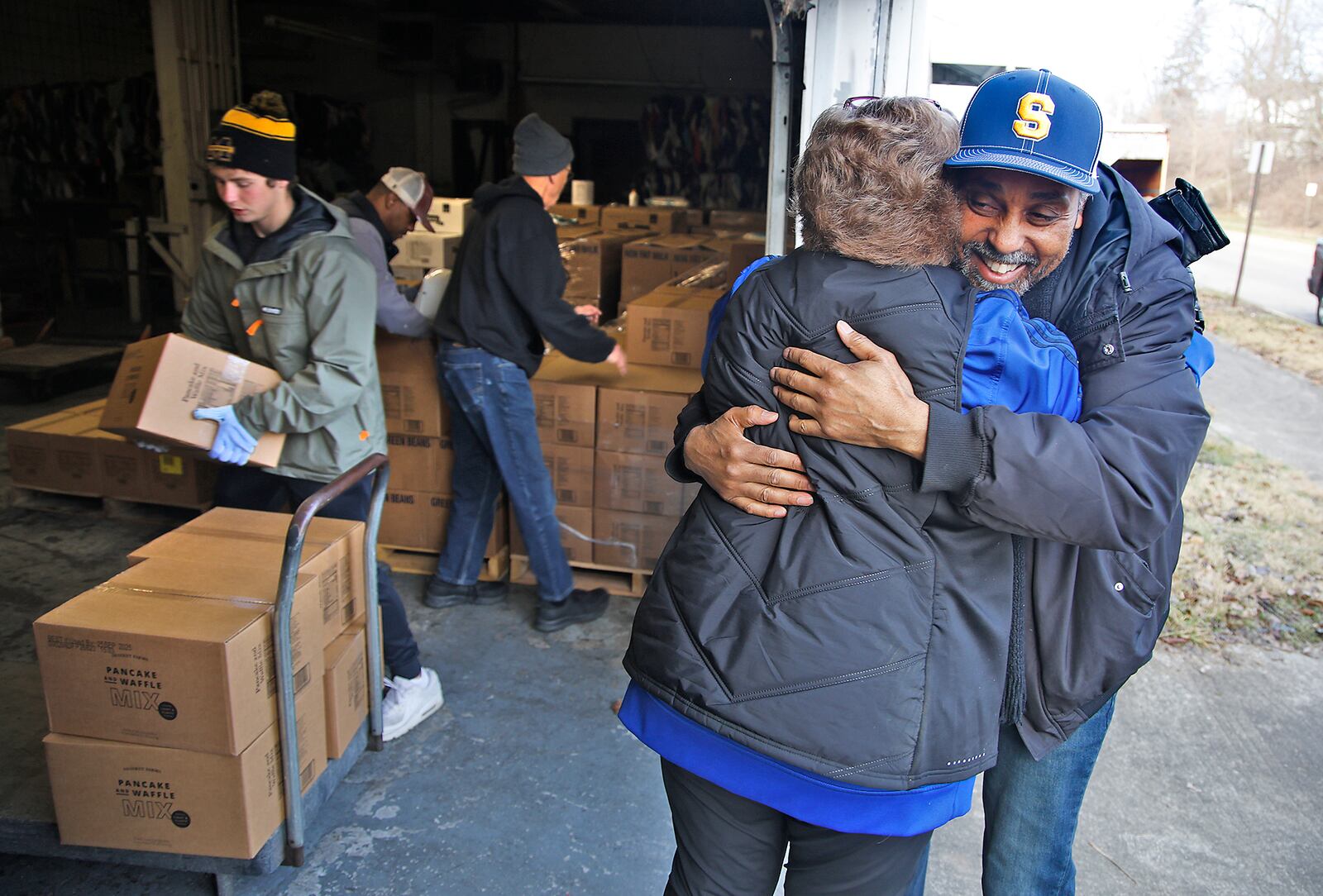 James Wallace, from Sheltered Inc., hugs Casey Rollings, the St. Vincent De Paul executive director, as others load a cart with boxes of food Wednesday, Jan. 3, 2024 at the St. Vincent warehouse. Food pantries from around the area are getting some extra help after St. Vincent recieved a 40,000 pound food donation from the Church of Jesus Christ of Latter-Day Saints. BILL LACKEY/STAFF