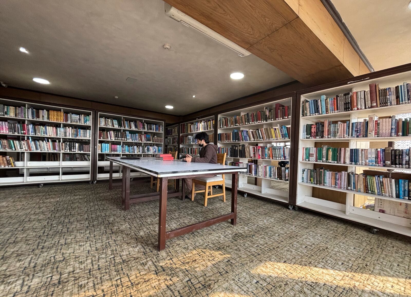 A man reads a book inside a library in Srinagar, Indian controlled Kashmir, Monday, Feb. 17, 2025. (AP Photo/Mukhtar Khan)