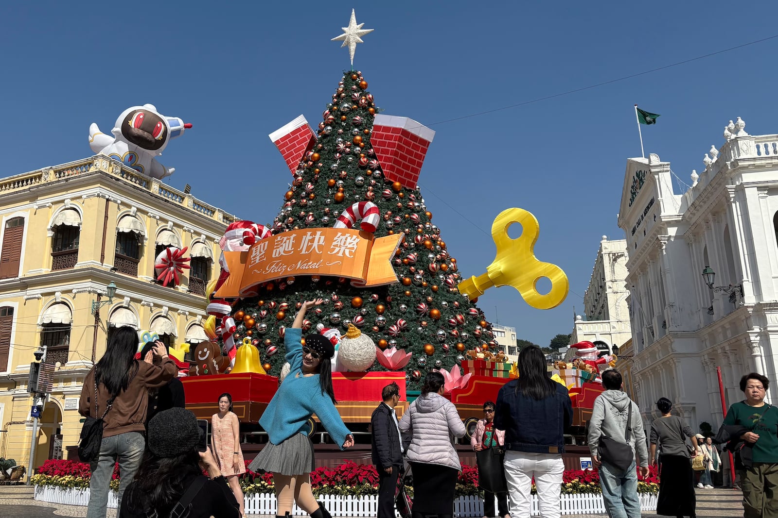 Mainland Chinese tourists take photos in front of a Christmas installation in Macao's historic Senado Square on Dec. 13, 2024. (AP Photo/Kanis Leung)