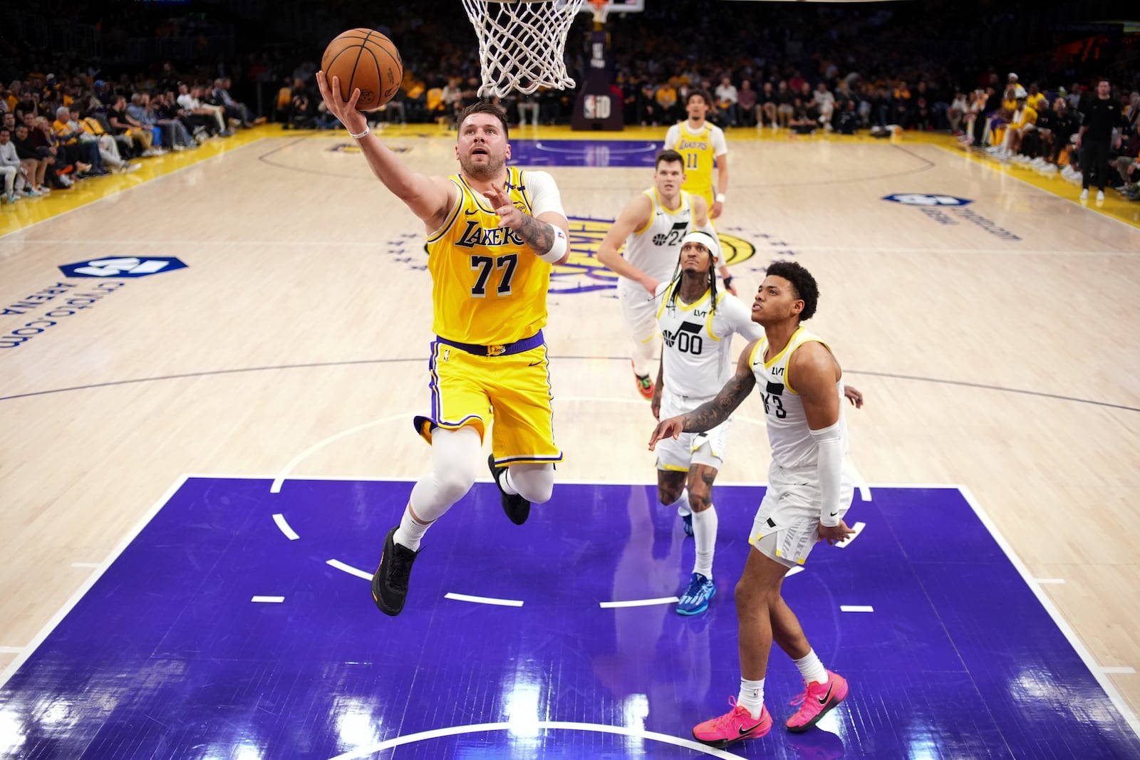 Los Angeles Lakers guard Luka Doncic (77) shoots as Utah Jazz guard Jordan Clarkson (00) and guard Johnny Juzang defend during the first half of an NBA basketball game, Monday, Feb. 10, 2025, in Los Angeles. (AP Photo/Mark J. Terrill)