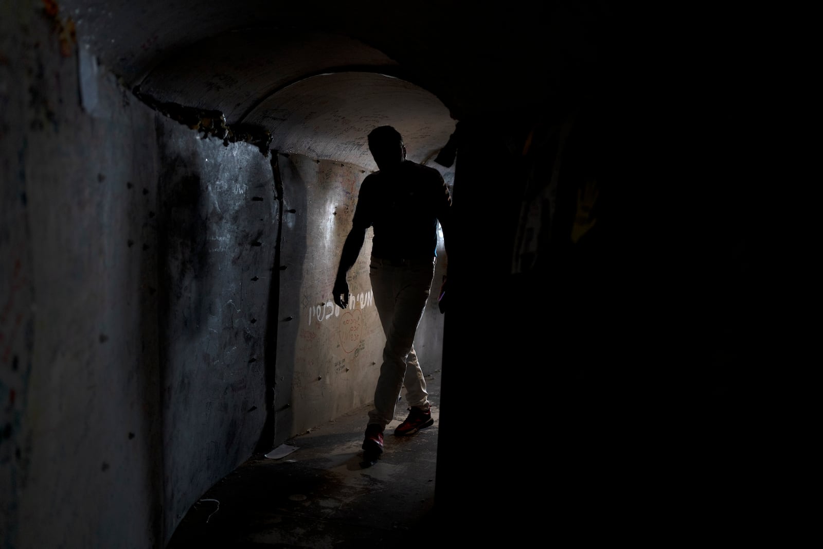 A visitor walks through a replica of a tunnel built by Hamas militants in the Gaza Strip, in a square in Tel Aviv, Israel that is a gathering point for families of hostages held by the militant group, Thursday, Nov. 14, 2024. (AP Photo/Maya Alleruzzo)