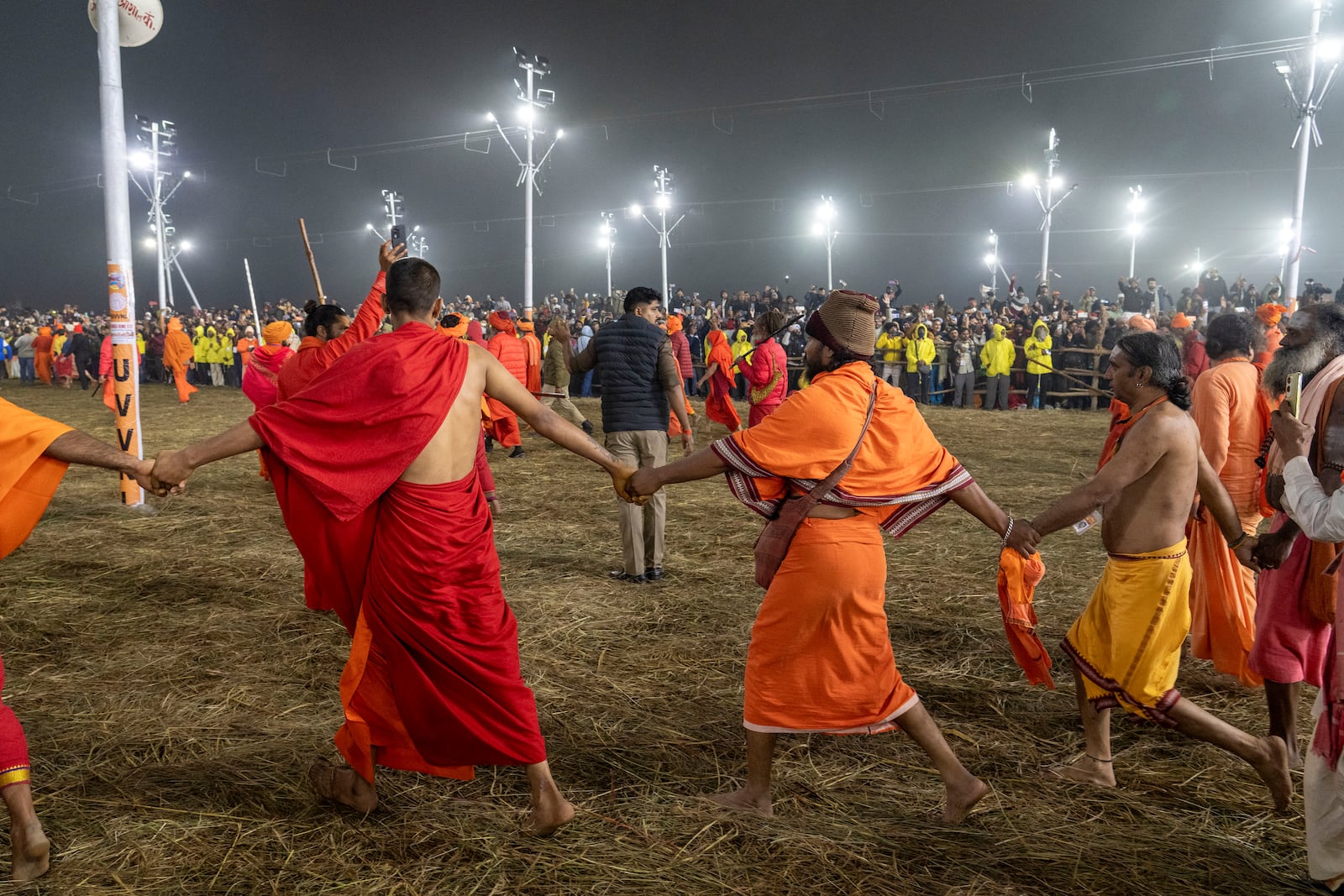 Followers make a barrier to the path on which senior Hindu ascetics and holy men walk in a procession to bathe at the confluence of the Ganges, the Yamuna and the mythical Saraswati rivers on the second day of the 45-day-long Maha Kumbh festival in Prayagraj, India, Tuesday, Jan. 14, 2025. (AP Photo/Ashwini Bhatia)