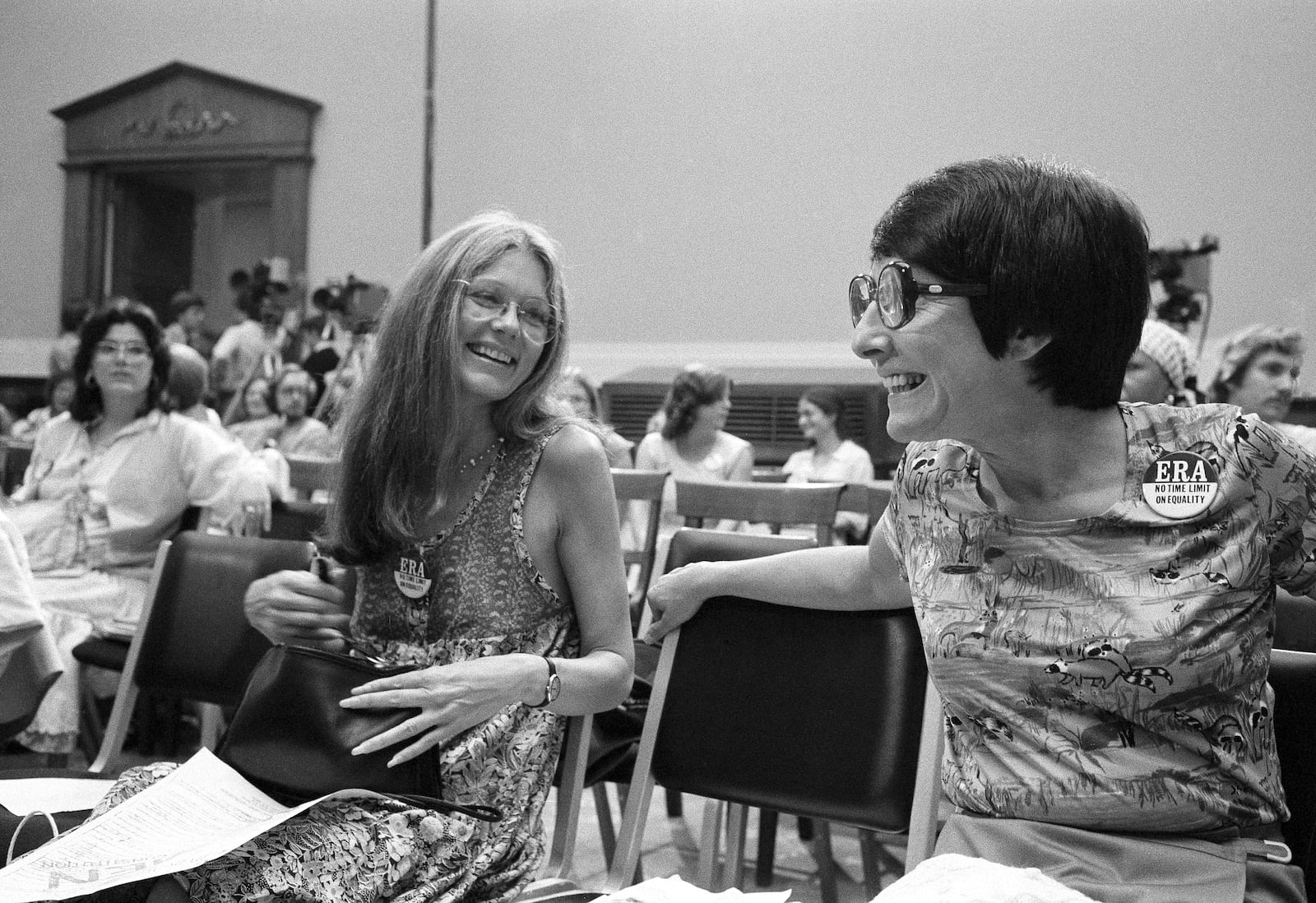 FILE - Gloria Steinem, left, and presidential assistant Midge Costanza laugh during a meeting of the House Judiciary Committee in Washington, July 18, 1978. The panel voted in favor of a time extension for ratification of the Equal Rights Amendment. (AP Photo/John Duricka, File)