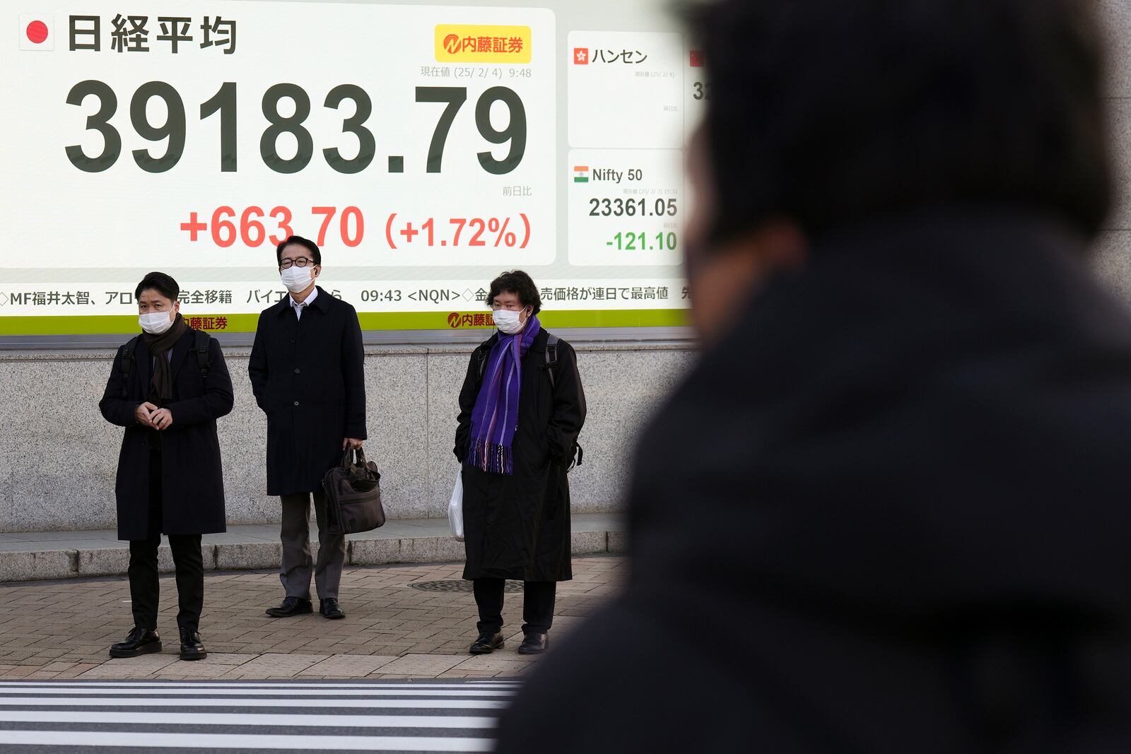 People stand in front of an electronic stock board showing Japan's Nikkei index at a securities firm Tuesday, Feb. 4, 2025, in Tokyo. (AP Photo/Eugene Hoshiko)