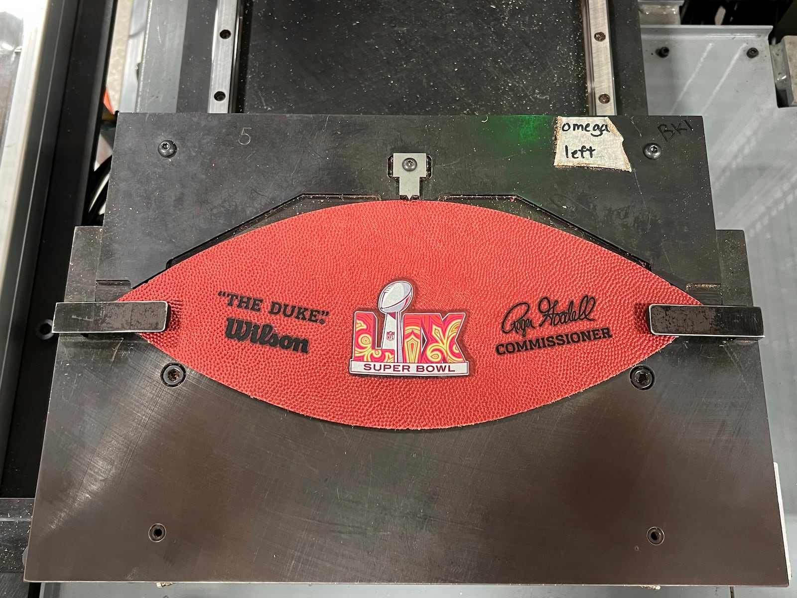 A part of a football for the upcoming Super Bowl matchup between the Philadelphia Eagles and the Kansas City Chiefs sits on a machine at the Wilson Sporting Goods football factory, Monday, January 27, 2025, in Ada, Ohio. (AP Photo/Patrick Aftoora-Orsagos)