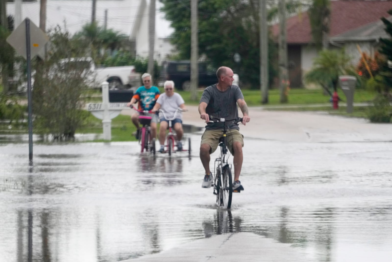 FILE - Cyclists ride through flooded streets in a neighborhood damaged by tornados spawned ahead of Hurricane Milton, Oct. 10, 2024, in Fort Pierce, Fla. (AP Photo/Wilfredo Lee, File)