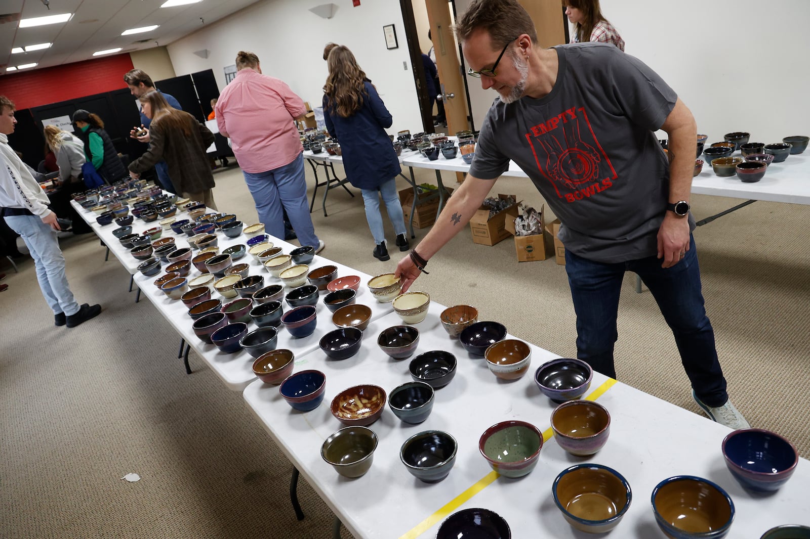 Scott Deeley, professor of art at Wittenberg University, checks out the bowls for sale Thursday, March 23, 2023 at the Empty Bowls fundraiser at the university. During the 28th annual Empty Bowls event, hosted by the Wittenberg Art Department in conjunction with Second Harvest Food Bank of Clark, Champaign and Logan Counties, attendees got to choose one of 1,000 unique bowls created locally for $20 and enjoy one of nine soups and bread in the company of other community members. The money from the event helped Second Harvest Food Bank food hungry residence in the community. BILL LACKEY/STAFF